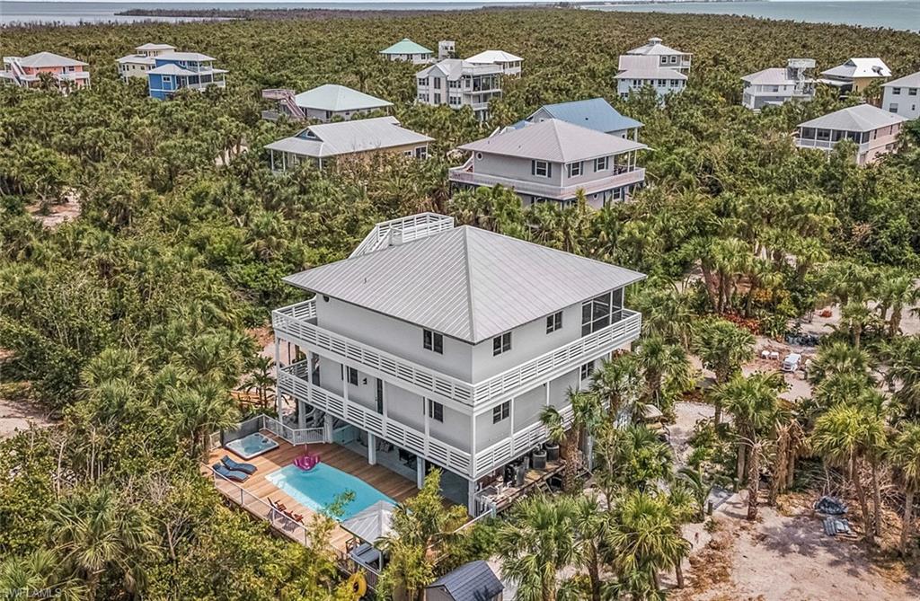 Exciting opportunity to own a private island retreat on one of North Captiva Island’s premier streets.  Nestled among mature tropical landscaping, 4490 Oyster Shell Drive offers exceptional privacy, a spacious 2,300 sq ft floor plan, and a proven rental history. This beautifully maintained 4-bedroom, 3.5-bath home features two en-suite bedrooms, inviting living spaces, and an exceptionally large private pool and hot tub surrounded by lush foliage—perfect for relaxing or entertaining. Recent updates include durable Hardie plank siding, low-maintenance Trex decking, and two HVAC units for enhanced comfort and efficiency. Located on prestigious Oyster Shell Drive, the property also offers the unique opportunity to purchase the neighboring lot, providing additional privacy, future expansion potential, or the creation of a private island compound. A rare combination of a more elevated island location, space, upgrades, and investment opportunity on North Captiva.