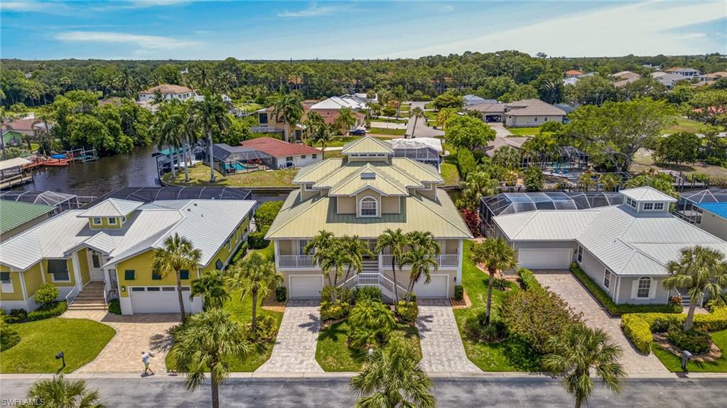 Discover an extraordinary waterfront retreat in Paradise Village, an intimate gated enclave of just 40 homes in the heart of Bonita Springs. This custom-designed, turnkey furnished Gulf access residence offers more than 3,000 square feet of thoughtfully crafted living space, seamlessly blending luxury, privacy, and the quintessential Southwest Florida boating lifestyle. Occupying the entire third level, the private owner's sanctuary is a true retreat unto itself. Featuring soaring ceilings, a spacious bedroom and sitting area, an oversized walk-in closet, and a spa-inspired bathroom, complete with a soaking tub, tiled walk-in shower, dual water closets, and dedicated dressing vanity, this exceptional suite is designed for comfort and relaxation. A private screened balcony off the bedroom area provides a tranquil setting to enjoy gentle breezes. The main living level is equally impressive, offering an open-concept design ideal for both everyday living and entertaining. The spacious great room flows effortlessly into the well-appointed kitchen and casual dining area, while three generously sized guest bedrooms and two full bathrooms provide comfortable accommodations for family and visitors. A screened balcony extends the living space outdoors, creating the perfect backdrop for morning coffee or evening cocktails. Outside, a resort-inspired setting awaits. The heated pool and integrated spa are surrounded by an expansive lanai with both shaded and sun-drenched spaces designed for entertaining and relaxation. A welcoming front porch offers the perfect vantage point for breathtaking Southwest Florida sunsets, while multiple outdoor living areas capture spectacular sunrises throughout the day. For boating enthusiasts, the property features a private dock and 6,000-pound covered boat lift situated on a navigable canal with direct access to the Imperial River. Cruise through the revitalized Downtown Bonita Springs waterfront district, enjoy waterfront dining, or continue westward to the Gulf of Mexico for endless days of boating, fishing, and exploring Southwest Florida's coastal waters. The ground level boasts an impressive five-car tandem garage, providing abundant space for automobiles, golf carts, paddleboards, kayaks, and all of your recreational toys. Ideally located just off West Terry Street, residents enjoy convenient access to the area's illuminated multi-use pathway connecting to the vibrant and ever-evolving Downtown Bonita Springs district, home to charming cafés, boutique shops, restaurants, entertainment venues, and community events. Bonita Beach and Barefoot Beach are just a short drive away, offering some of Southwest Florida's most celebrated stretches of sugar-white sand. Rarely does a property combine Gulf access boating, luxury living, generous garage space, and a prime Bonita Springs location so effortlessly. This exceptional Paradise Village residence presents a unique opportunity to experience waterfront living at its finest.