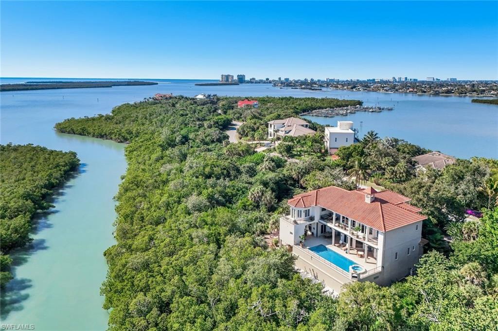 Paradise is redefined at this elevated waterfront estate, where timeless coastal design meets panoramic views of Caxambas Bay and Little Tide Key. Set approximately 25 feet above sea level on a private half-acre with southern exposure and protected shoreline, the property offers a level of peace, privacy, and natural beauty rarely found. Designed for seamless indoor-outdoor living, this three-story residence features multiple terraces capturing both sunrise and sunsets. The thoughtfully designed floor plan includes five bedrooms, five full baths, and two half baths, with two primary suites on separate levels. Over 6,300 square feet of air-conditioned living space including a family room, living room with fireplace, and a lower-level entertainment area with media lounge and game space, complemented by over 11,300 square feet of total area. Resort-style outdoor amenities include an oversized pool and spa, sauna, outdoor kitchen, propane fire feature, and outdoor shower. Additional features include climate-controlled storage, a 4.5-car garage, and lush, private grounds with native and fruit-bearing plantings. Behind the gates of historic Key Marco, life unfolds at a slower, more refined pace with access to a private boat slip, resort-style amenities, and miles of tranquil trails. Minutes from modern conveniences yet worlds away, this is a rare opportunity to experience unmatched privacy, natural beauty, and timeless coastal living.