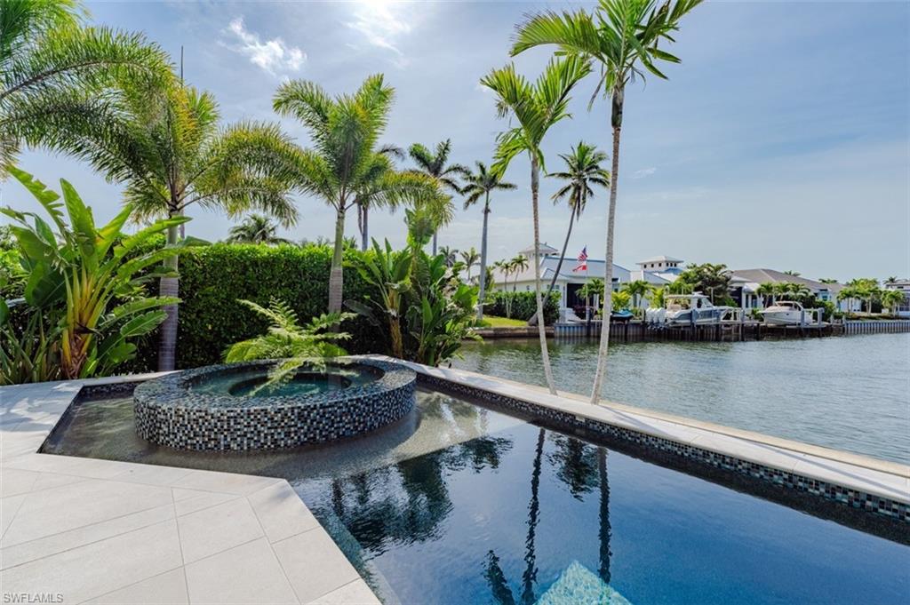 Experience the epitome of luxurious coastal living in the highly coveted Royal Harbor community! This immaculate, nearly-new coastal contemporary home is a stunning blend of innovative design and unparalleled functionality. As you step inside, you're welcomed by an exquisite custom residence where ultimate comfort seamlessly integrates with cutting-edge sophistication. Equipped with a state-of-the-art Lutron lighting system, advanced security cameras, and a spacious, oversized three-car garage, this home is built with both convenience and security in mind. Indulge in resort-style amenities that cater to every need, including a breathtaking pool and spa area, a cozy gas fireplace, and a climate-controlled wine room that will delight any connoisseur. The heart of this home lies in its true chef’s kitchen, featuring top-of-the-line Thermador appliances, including a 48” range with oven, steam oven, warming drawer, and a counter-depth refrigerator/freezer. Two expansive islands provide ample storage and maximize functionality, making it the ideal space for culinary creations and entertaining. Host guests in style with an open-concept living and dining area that flows seamlessly to the outdoor living space, where you'll find a fully equipped kitchen with a gas grill. The glamorous infinity-edge pool and spa provide a tranquil setting for relaxation and entertainment, while stunning views enhance the experience. Boating enthusiasts will appreciate the custom dock, complete with a 13,000-pound boat lift, a 15’ x 15’ elevator lift for jet skis and kayaks, and a cozy seating area, making this the ultimate waterfront haven. Located just minutes from the renowned 3rd Street South and 5th Avenue South, this residence offers easy access to world-class shopping, fine dining, and pristine white sand beaches. This exceptional home is a true sanctuary for those who seek the finest in coastal contemporary living, offering a rare opportunity to enjoy the ultimate lifestyle.
