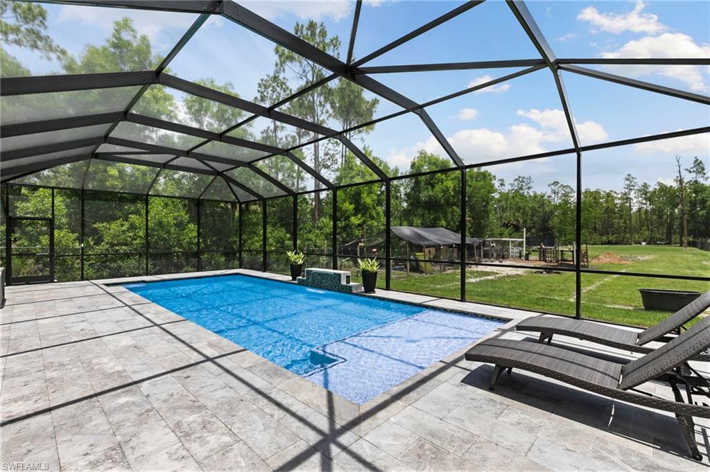 New construction? Check! Massive pool? Check! Complete privacy? Check! This home has it ALL and is truly a MUST SEE! Beautifully upgraded, fully fenced and gated, this exceptional property is designed for elevated comfort, complete privacy, and versatility. Showcasing a seamless blend of thoughtfully curated custom upgrades, the home offers exceptional indoor living, outdoor functionality, and resort-style outdoor spaces. The extended driveway comfortably accommodates up to 10 vehicles, while additional side fencing creates a thoughtful separation between the front and backyard for enhanced privacy and flow. The property also offers exceptional access to the rear yard for vehicles, boats, and recreational equipment, making everyday use and storage incredibly convenient.

Inside, the home features upgraded tray ceilings with wood beams, a built-in electric fireplace, window treatments throughout, two walk-in closets, a stunning primary bathroom, whole-house reverse osmosis water filtration, and an ADT security system already in place. 

Step outside to your outdoor oasis featuring a massive heated saltwater pool with a sun shelf, waterfall feature, upgraded travertine decking, and a fully screened enclosure. The pool deck was extended an additional 9 feet to maximize Year-Round sunlight exposure, and the entire system is app-controlled for modern convenience. The property has been extensively cleared and professionally landscaped, including a newly planted poinciana tree and full irrigation systems servicing both the front and back yards. An outdoor kitchen setup creates an ideal setting for entertaining, while the overall layout offers complete privacy and usable space throughout the entire lot.

For those seeking versatility, the property includes a chicken coop, a covered structure ideal for animals, equipment, or additional storage, and a fully fenced enclosure with a private pond, lush botanical-style plantings, and a misting sprinkler system creating a serene, park-like environment unlike anything else. Conveniently located less than 5 minutes from the new Vanderbilt Beach Road extension, this one-of-a-kind property combines space, upgrades, privacy, and lifestyle flexibility. A recent 4-point inspection has already been completed for added peace of mind!