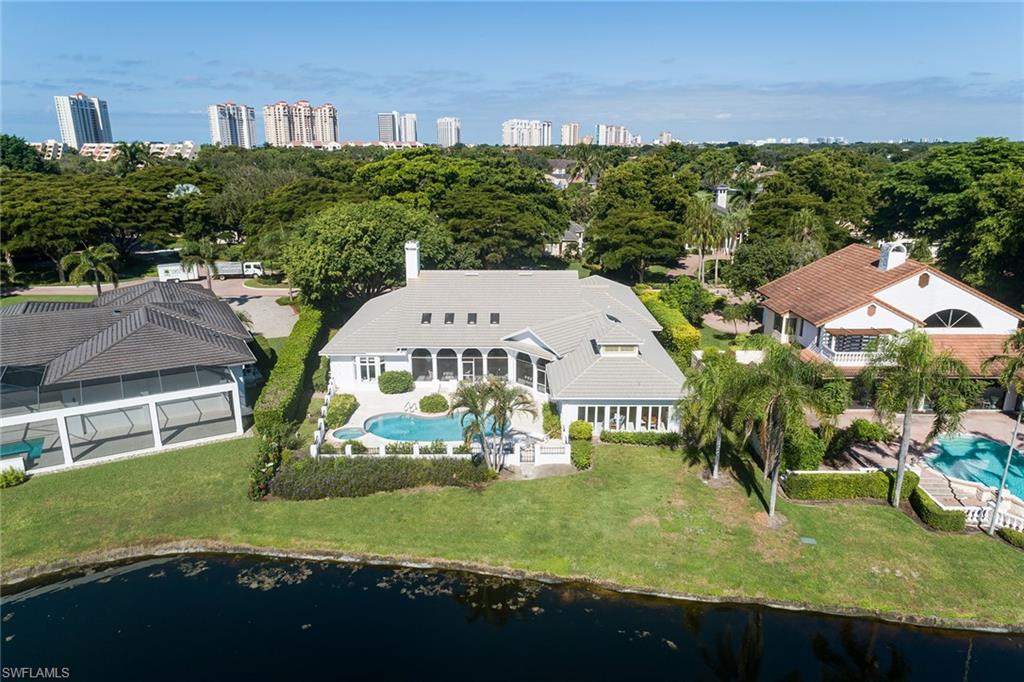 Perched on one of the most prime lots in all of Pelican Bay, 708 Nathan Hale is a sundrenched jewel box that sits on a southern exposure 0.42-acre lot, in the preferred X flood zone, with long sparkling lake and panoramic vistas in the sought-after gated enclave of Georgetown. This home exudes charm and timeless Old Florida flavor with a floor plan that rivals today's open living spaces with soaring 16-foot ceilings, large windows and 8-foot pocket sliding doors. The fine woodwork and architectural detail abound throughout the home and every space is supersized, offering a total of over 4,500 square feet under air and over 8,400 in total area. The dramatic signature fireplace and built-ins define the space beautifully. The covered screened piazza is massive (over 700 square feet) and overlooks the sparkling lake views and large pool, spa and deck space. The versatile and extremely sunny guesthouse offers 800 square feet, beamed ceilings, an abundance of floor-to-ceiling windows, large open space, full kitchenette and large bath. Roof was installed in 2015, electric and manual hurricane shutters, circle driveway, oversized garage with extra storage, and no flooding during Hurricane Ian completes the package. Georgetown is one of the prized gems of Pelican Bay, with its interior, sound-proof location, gorgeous, oversized lots, loads of brand-new homes mixed with classic, timeless homes, and a 24 hour guard-gated entry. Pelican Bay residents also benefit from a myriad of five-star amenities, including two fabulous newly renovated beachfront restaurants, tennis courts, pickleball, biking and recreational trails, and a state-of-the-art fitness and life center with a full gym, spin classes, yoga and more. Indulge in a lifestyle of elegance and sophistication in this Pelican Bay gem!