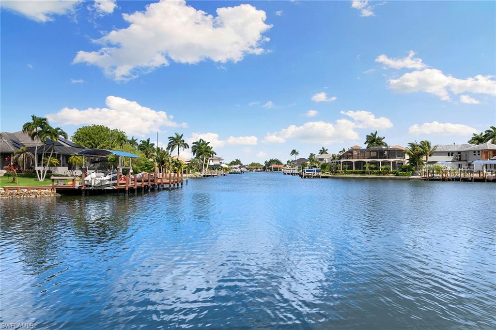 Enjoy coastal waterfront living in this beautifully updated three-bedroom, three-bath home, featuring stunning wide-water open views, sunset skies and easy direct access to the Marco River. A welcoming front porch opens to a classic coastal-style interior with vaulted ceilings and separate living and dining areas. The updated kitchen features a breakfast bar, custom cabinetry, pantry, induction range and granite countertops, flowing seamlessly into a comfortable family room. Upstairs, the loft provides flexible space for a den or recreation room and includes a private balcony with access to an observation deck, an ideal spot to enjoy stunning views and watch dolphins play. Tile and wood flooring throughout add style and easy maintenance. A large paver, clear-view screened lanai with a sparkling pool creates an inviting space for relaxing or entertaining. For the boating enthusiasts, the property also includes a new dock installed in 2021, complete with 15,000-pound boat lift and 5,000-pound platform lift for jet skis, kayaks or other watercraft. The sunning deck is the place to soak in the magnificent views and enjoy a day by the water. Recent updates include a new metal roof installed in 2019 and a new air conditioner in 2023. Impact glass windows and doors. The seawall has been reinforced with new cap. Embrace the island lifestyle in this exceptional home.