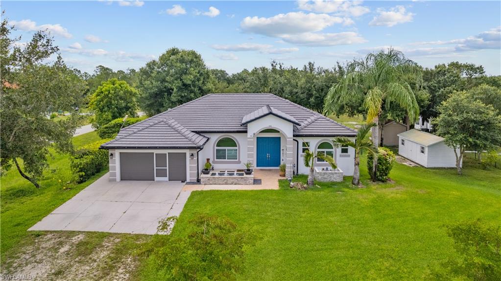 Rarely does an opportunity like this become available. Situated on a desirable 2.8-acre corner homesite with no HOA, this well-maintained property offers privacy, space, and convenience just minutes from a new Publix and everyday amenities. Recent updates include a new water heater, Frigidaire Gallery refrigerator and microwave (2025), updated bathrooms, a flat tile roof (2020), hurricane-impact windows, and roll-down hurricane protection on the screened lanai. Inside, soaring 10-foot ceilings, a tray ceiling in the primary suite, updated window coverings, ceiling fans throughout, and a spacious walk-in pantry create a comfortable and inviting living environment. Outside, enjoy a tropical setting with avocado and papaya trees, a pineapple garden, mature shade trees, a partially fenced yard for pets, two storage sheds, and a stunning illuminated fountain feature that enhances the home's curb appeal at night. Additional highlights include a mini-split cooled garage, security system with exterior cameras, gutters surrounding the home, and a John Deere riding lawn mower included with the sale.