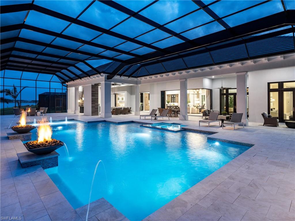 Move In Ready! Indulge in the epitome of luxury living at this magnificent "Savannah III" model Stock Custom Home, located on an expansive Eastern facing waterfront estate lot at 18280 Blue Eye Loop, designed and offered FURNISHED by the renowned designers at Soco Interiors. Spanning an expansive open-style layout with an impressive 4,616 SF under air, this residence is highlighted by thoughtful clean-lined architectural details that highlight this contemporary waterside home with wood accents mixed with warm driftwood and smokey tones. 4 beautifully appointed bedrooms each designed with great detail are accompanied with there own bathroom. 2 half bathrooms, a versatile den & 4-car epoxy floored garage with circular driveway also featured.  Impact windows & doors, wide plank wood flooring, spray foam insulation, great room custom fireplace wall, solid core four pane interior doors, spray foam insulation, 2 tankless water heaters, painted drywall beams, custom built-ins, home automation & lighting control are just a few features to mention. The open chef’s kitchen offers double islands, Quartz countertops with combo Quartz and Decrotive tile backsplash, natural gas stove, Sub Zero & Wolf Appliances. Adjacent Wet bar with U-line undercounted wine coolers. The dining and living areas offer stunning views of the waterfront, creating a serene and inviting atmosphere. The master suite offers a relaxing retreat, with high vaulted coffered ceiling and rich medium tones wood floors. Inviting master bath features a round free-standing tub, walk-in shower in a matte marble-look tile & dual sinks & polished chrome fixtures. Step outside to your private outdoor tropical oasis, where breathtaking panoramic views of a pristine freshwater lake await on your expansive panoramic screened lanai. The lavish heated saltwater pool with an integrated spa, sun shelf & waterfall fire bowls invites relaxation and leisure while the outdoor fireplace creates a cozy ambiance to cooler evenings. This outdoor living space offers a seamless connection to the inside, with custom beam ceilings & large dining table conveniently next to the outdoor kitchen, refrigerator & Ice maker. Residents of Wildblue enjoy a wealth of resort style amenities featuring over 800 acres of freshwater lake, 8 pickleball courts, exercise room, lap pool, spa, clubhouse, tennis, spa, nail salon, kayak & boat launch, walking trails, outdoor grille, bar & much more! With no expense being spared, this exquisite residence represents a rare opportunity to experience the best that Southwest Florida has to offer. The oversized waterfront estate lot offers stunning views and a tranquil setting, making this residence a true oasis. Experience the ultimate in luxury living at 18280 Blue Eye Loop, where every detail is designed to provide an unparalleled lifestyle of elegance and comfort. Claim your slice in paradise today!