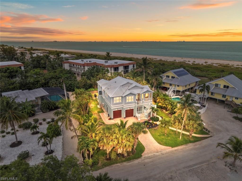 Perfectly positioned on Sanibel Island's coveted east end, just one property from the Gulf, this exceptional custom-built coastal residence offers a rare combination of refined luxury, uncompromising construction, and an enviable island lifestyle. A private path leads directly to one of the world's most celebrated shelling beaches, while the coveted east-end location provides convenient on-and-off island access and a short stroll to the charming Lighthouse District with its boutiques, restaurants, and marina. Thoughtfully designed to embrace its extraordinary setting, the elevated home is built on concrete pilings and constructed to withstand Florida's coastal environment with impact-rated windows and doors, a standing seam metal roof, and durable Hardie siding and trim. From nearly every room, sweeping Gulf views create a breathtaking backdrop.
The interior reflects timeless coastal sophistication, where soaring coffered vaulted ceilings, exquisite custom millwork, and solid-core 9-foot doors define the living spaces. Walls of glass welcome abundant natural light, seamlessly connecting elegant interiors with the beauty beyond.

At the heart of the home, the chef's kitchen is both functional and stunning, appointed with premium appliances including a built-in refrigerator, French-door chef's oven, induction cooktop, and an expansive island designed for effortless entertaining. The elevated dining space is enveloped by mullioned glass and panoramic water views that transform every meal into an unforgettable experience.

The expansive great room is filled with warmth and light, framed by spectacular Gulf vistas and beautifully detailed architectural finishes. Screened lanais at both the front and rear invite year-round indoor-outdoor living, where gentle sea breezes and the soothing sound of the surf create a setting of remarkable tranquility.

Beyond, the private outdoor retreat centers around a custom heated pool and spa with a tranquil water feature and elegant travertine surround—an idyllic place to relax after a day on the beach or exploring the island by boat or bicycle.

Completing the property is an oversized 6-plus-car garage, offering exceptional space for collectors, boating enthusiasts, golf carts, bicycles, and every necessity of the island lifestyle.

Offering extraordinary craftsmanship, breathtaking Gulf views, direct beach access, and one of Sanibel's most desirable locations, this remarkable residence is more than a home—it is a legacy property where luxury, serenity, and the timeless beauty of island living exist in perfect harmony.