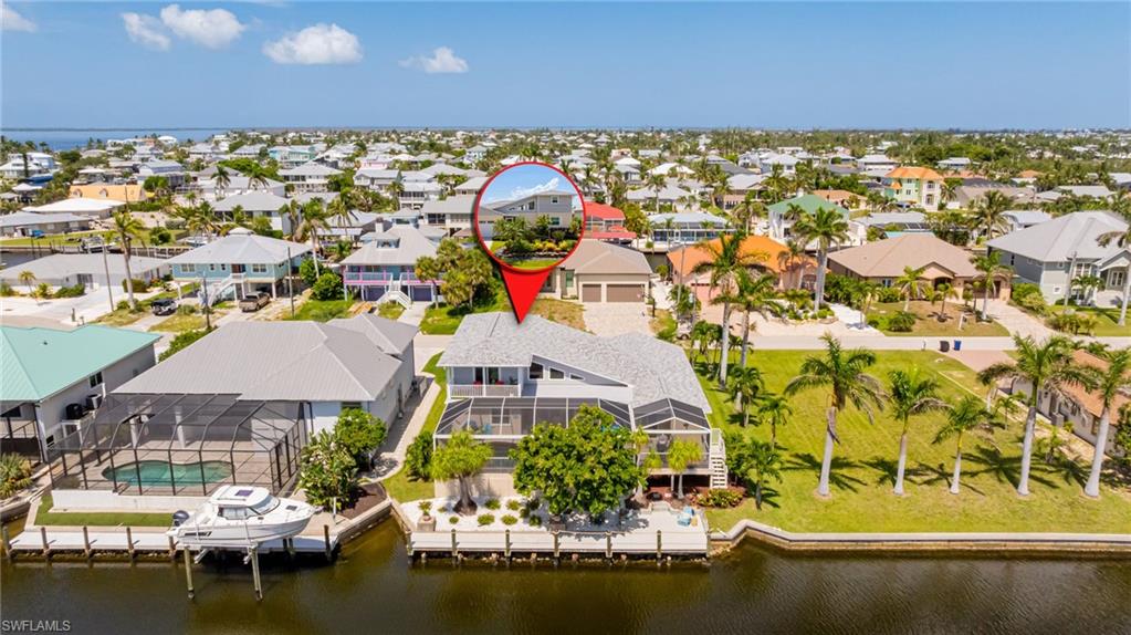 Experience true coastal luxury in this beautifully remodeled 3BD/3BA waterfront retreat in Saint James City with direct Gulf access—no bridges. Located just north of the Sanibel Causeway, this elevated oasis offers 2,383 sqft of open living, soaring ceilings, & 5 sets of impact sliding doors for seamless indoor-outdoor flow. The east-facing lanai features a heated pool, large screened cage, & full outdoor kitchen w/quartz island, grill, bar fridge & burners --perfect for shaded afternoons & evening entertaining. Inside, enjoy two primary suites (1 up,1 down), an additional bedroom, plus a loft & private balcony. All 3 spa-inspired baths feature rainfall showers, a freestanding tub & designer finishes. Smart home features include Samsung Bespoke washer/dryer, 4-door Flex fridge, Ring, Nest, & more. Built on 10-ft elevation, no flood issues, with impact windows/doors, 2023 roof, new garage door, composite dock (2021), plantation shutters, Minka Aire fans, custom closet systems & lush tropical landscaping w/lighting & irrigation. This home is your private boating paradise! Move-in ready & unforgettable.