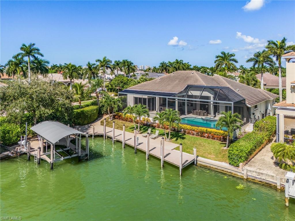 Exquisite Waterfront Estate on Roberts Bay in Marco Island with direct Gulf Access and southern exposure. Welcome to your own slice of paradise on Marco Island's most desirable waterfront locations. This lavish waterfront residence offers panoramic canal and wide water views with immediate deep water access to the Gulf of America through Caxambas Pass, no bridges required. A true boater's dream, this home delivers luxury, comfort, and coastal elegance in every detail, where dolphins, manatees, and tropical fish are your daily neighbors. Step through the grand double doors and be greeted by a dramatic wall of windows framing the sparkling infinity-edge heated salwater pool and spa, blending the beauty of the bay beyond. The open concept design fills the home with natural light, while coffered ceilings, custom built-ins, plantation shutters, and Vietnemese hardwood and marble floors showcase timeless craftsmanship and style. This 3-bed +den, 3.5-bath home with a 3-car garage is designed for island living. The chef's kitchen takes center stage with granite countertops, a spacious island, stainless steel appliances, walk-in pantry with pullouts, breakfest nook, and built-in desk all oriented to capture magnificient waterfront views. Every bedroom offers walk-in closets, ensuring ample storage and comfort for family and guests. Entertain with the zero-corner sliding doors that open completely to a spectacular outdoor living area. Under the warm glow of a rich hardwood ceiling, you'll find an outdoor kitchen with bar, built in grill, and TV, perfect for al fresco dining, big game party, or relaxing evenings watching boats glide by. The expansive lanai features multiple seating and dining areas, creating an ideal setting for gatherings large or small. Outside, the boater's amenities are second to none! With 136 ft of seawall, wraparound dock, 60-ft yacht slip with tide guides, covered 13,000-lb boat lift, captain's walk, and 50-amp shore power with water plus a fish cleaning station, this private dock is built to accomodate vessels of all sizes. Launch your boat for a day of fishing or a sunset cruise straight to the Gulf-no bridges, no limits! Added highlights: remote-controlled hurricane shutters across lanai, two underground propane tanks (500gal each) servicing the pool heater, outdoor grill and indoor fireplace, central vacuum system, and no HOA. The primary suite offers a private retreat with lanai access, a spa-inspired bath with dual sinks, jetted tub, and walk-in shower, and a large safe discreetly placed in main closet. The laundry room includes an ice machine, second fridge, and side entry to a screened porch leading directly to the dock - perfect for storing fishing, scuba, or kayak gear, doubling as a flex space for your pets, hobby area, or garden workspace. From the sunrise reflections on the bay to tranquil evenings by the infinity pool this residence captures the very best of coastal Florida living. Welcome home to Marco Island.
