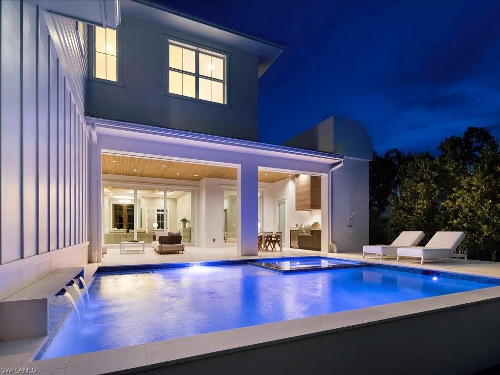 Positioned on a quiet interior street in Old Naples’ Lake Park, 1179 Broad Avenue North presents a rare opportunity to own a newly completed 2025 custom residence, never lived in and thoughtfully designed for refined coastal living just moments from Fifth Avenue South, Third Street South, and the Gulf’s white-sand shoreline. Spanning 4,669 square feet, this five-bedroom plus den estate offers an effortless balance of scale and intimacy, anchored by a ground-floor primary suite with a private sitting area and a spa-inspired bath. Upstairs, a secluded loft and guest wing create a distinct retreat for visitors. The open-concept great room is framed by expansive sliders that dissolve into a screened lanai, revealing a heated saltwater pool and spa, a fully appointed outdoor kitchen with gas grill, fireplace, and outdoor shower—an elegant expression of Naples’ signature indoor-outdoor lifestyle. At the heart of the home, the kitchen is both functional and striking, appointed with a Thermador appliance suite, quartzite countertops, an oversized island, walk-in pantry, and a wet bar with wine refrigeration. Interior finishes include wide-plank wood and large-format tile flooring, coffered and volume ceilings, custom millwork, a sculptural staircase, integrated surround sound, and a gas fireplace. Constructed for enduring quality, the residence features solid concrete block construction on both levels, a standing seam metal roof, impact-resistant windows and doors, electric storm shutters, zoned HVAC with whole-house humidity control, tankless water heating, propane service, and a three-car garage with a circular paver drive. With no HOA and a coveted in-town location, this is a compelling offering for those seeking a newly built Old Naples address with enduring design and effortless proximity to the area’s most celebrated dining, shopping, and coastal experiences.