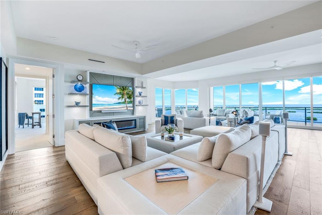 This luxurious fully furnished turn-key high-rise condominium offers a stunning blend of comfort and opulence. Situated in the exclusive OMEGA at Bonita Bay community, this 19th floor end unit boasts breathtaking views of the bay, golf course, and endless water views making it a prime piece of real estate in SW Florida. Built in 2022, it encompasses an impressive interior living space of 4645 square feet and with its expansive terraces and adjacent storage, totals over 5700 square feet. It features four bedrooms plus a den and five bathrooms, including four full baths and one half bath. The design of the unit emphasizes both luxury and functionality, with a private elevator that opens into an entry foyer enhanced with custom built-ins.  The main living areas of the condo are adorned with high-end furnishings from Restoration Hardware, complemented by deep blue art pieces and accent decorations that enhance the sophisticated ambiance. The light and white great room furniture accents the beautiful hardwood floors that run throughout these areas, and along with its fireplace offers a rich, warm tone that adds to the home's welcoming atmosphere. The kitchen is a chef's dream, featuring two islands, huge walk-in pantry, upgraded tile back-splashes, and flooring, with designer light fixtures casting a soft, inviting glow. Adjacent to the kitchen, the diningroom is enveloped by a custom blue textured wall covering, further accentuating the elegant aesthetic.  One of the condo's standout features is its outdoor terrace, which includes a well-appointed kitchen perfect for al fresco dining and entertaining while enjoying the panoramic views. Custom power window coverings are installed with both beauty and energy efficiency in mind. One of the most sought-after features is that 2 pets, of any size, are allowed for owners. This condo offers a range of resort-style amenities that cater to a luxurious lifestyle. These include a stunning rooftop lounge, a community pool & pavilion, theatre, billiard room, and a variety of social activities, ensuring residents have access to both relaxation and entertainment. The building itself is designed with 67 units spread across 27 floors, with this unit occupying an end unit on 19th floor. The property includes two attached garage spaces, providing ample parking. Residents have the option to enjoy the various amenities offered within the Bonita Bay community, such as a private beach club, bike and jog paths, and a marina. The community also features the option of an adjacent golf course, tennis courts,  bocce courts, a business center, beauty salon and much more, making it a vibrant and active place to live.