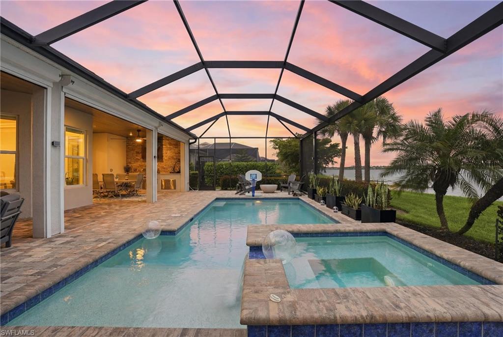 This one is a true showstopper and a must-see! Experience refined lakefront living in this exceptional Bougainvillea floor plan residence located within the highly sought-after resort-style community of WildBlue. Offering 4 bedrooms, 3 full baths, a private study, and an open-concept design, this move-in-ready, fully turnkey furnished masterpiece seamlessly blends luxury, comfort, and the ultimate Southwest Florida lifestyle.

Perfectly positioned on one of WildBlue's pristine lakes, this stunning waterfront property offers the rare opportunity to boat directly from your backyard private dock and explore miles of scenic boating waters. The oversized double dock is equipped with power, water, and integrated lighting, plus two floating jet ski docks, making it ideal for boating, paddleboarding, kayaking, fishing, or simply enjoying life on the water.

With over $200,000 in premium upgrades, every detail of this home has been thoughtfully designed. The expansive outdoor living space features a sparkling pool and spa, outdoor kitchen, spacious covered lanai, breathtaking sunrise views, and a propane gas fireplace surrounded by premium Polywood furnishings. The lanai showcases elegant tongue-and-groove ceilings and a custom built-in outdoor entertainment center with fireplace, creating the perfect setting for year-round entertaining and relaxation. Custom landscaping and landscape lighting enhance the home's beauty and curb appeal.

Inside, the home is loaded with luxury finishes including white cabinetry, premium appliances, a large center island, Bahama shutters, stone exterior accents, custom paint, designer lighting, custom ceiling fans, upgraded mirrors, custom shower doors, and countless designer touches throughout. The spacious great room flows seamlessly into the gourmet kitchen and outdoor living area while featuring a stunning custom shiplap indoor entertainment wall with built-in fireplace.

Being offered fully turnkey furnished, this residence allows the next owner to immediately enjoy the coveted WildBlue lifestyle. The private study provides flexibility for a home office or media room. The owner's suite offers spectacular lake views, a spa-inspired bath, and generous closet space, while guest bedrooms provide comfort and privacy for family and visitors.

Additional upgrades include electric storm shutters, a full-house Generac generator, air-conditioned 3-car garage, custom epoxy garage flooring, and numerous high-end enhancements throughout. WildBlue offers world-class amenities including a clubhouse, restaurant, resort-style pool, fitness center, tennis, pickleball, lakeside beach, and miles of navigable boating waters. Conveniently located near shopping, dining, Gulf Coast Town Center, FGCU, and Southwest Florida International Airport, this extraordinary property delivers an unmatched combination of luxury, convenience, and waterfront living.