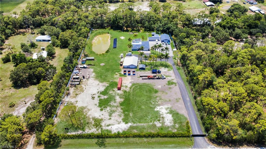 Experience the perfect blend of privacy, space, and functionality on this exceptional estate property! Situated on a sprawling, fully fenced parcel, this beautifully maintained residence offers a peaceful country setting while still being conveniently located near shopping, dining, and everyday conveniences.
The main home features an inviting open floor plan with spacious living areas, abundant natural light, and seamless indoor-outdoor living. Step outside to your screened pool area, perfect for entertaining or relaxing year-round while enjoying serene views of the expansive grounds.
A standout feature of this property is the impressive detached storage building/workshop, offering endless possibilities for business equipment, recreational vehicles, boats, car collections, hobbies, or additional storage needs. The oversized paved parking area provides ample room for trucks, trailers, RVs, and guests.

Additional highlights include solar panels for improved energy efficiency, a private pond, mature landscaping with beautiful palm trees, raised garden beds, and plenty of open space for outdoor activities. The property offers a rare combination of residential comfort and functional acreage, making it ideal for those seeking room to live, work, and play.

Whether you're looking for a private retreat, a place to store all your toys, or a versatile property with endless potential, this one-of-a-kind estate is a must-see!