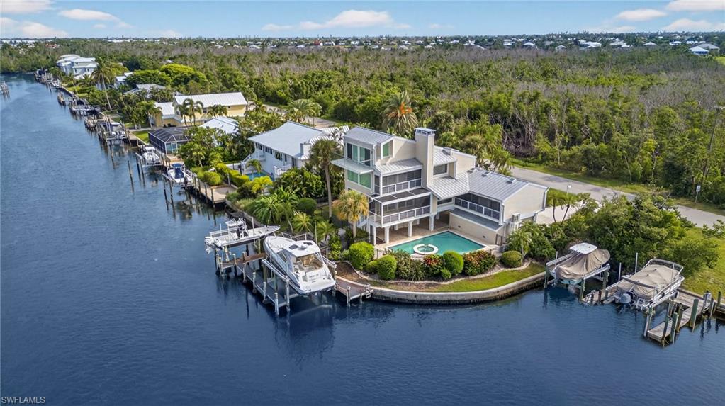 There are rare moments in real estate when location, architecture and lifestyle converge in harmony, and this is one of them. Tucked away at end of prestigious Bay Drive, a hidden harbor reveals itself: a serene boat basin with pristine, direct Gulf access. At its heart lies a private peninsula of sea walled land, graced by an awe-inspiring residence that feels as if it floats above the water. From nearly every room, panoramic views unfold, like vistas typically reserved for the bridge of a luxury yacht. Completely reimagined and masterfully remodeled, this home exudes refined coastal sophistication, designed to complement rather than compete with its extraordinary natural setting. Inside, walls of impact-rated glass and expansive impact sliders invite the outside in, filling each space with golden light dancing off the water. The interiors are elegant and effortless, stunning 24-inch tile flooring, wood-inlaid ceilings and a seamless flow between living, dining and kitchen areas designed for intimate gatherings and grand entertaining. The chef’s kitchen is a study in modern craftsmanship, featuring rich walnut cabinetry and exquisite Cristallo quartzite countertops, paired with top-tier appliances. Every detail whispers luxury, every glance reveals another breathtaking view. Go outside to an expansive lanai where an outdoor kitchen, sparkling pool and elevated spa overlook the tranquil basin. For boating enthusiasts, the private dock is nothing short of exceptional, complete with dual lifts (26,000 pounds and 16,000 pounds) to accommodate your vessels and your adventures. Ascend to the primary suite, where a cozy gas fireplace, serene seating area and private reading loft await. From here, the views of the bay and basin are nothing less than mesmerizing; a daily reminder of the unparalleled lifestyle this home affords. This is more than a residence, it’s a statement of timeless luxury and rare opportunity. A place where every sunrise and sunset reflects the best of coastal living; private, peaceful and profoundly beautiful.