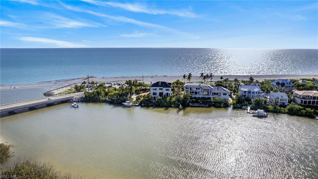 At the southernmost tip of Captiva Island, where the turquoise waters of the Gulf meet the tranquil expanse of Pine Island Sound, lies one of Southwest Florida’s extraordinary residential offerings. Encompassing more than an acre stretching seamlessly from Gulf to Bay, this private estate commands an exceptionally rare setting immersed in water, light and natural beauty from every direction. Beyond the gated entrance, a dramatic composition of architecture and landscape unfolds. A resort-style pool and spa, lush tropical grounds, and a private dock with boat lift create a lifestyle defined by effortless access to the open Gulf and protected waters of the bay. Few properties can claim such a remarkable dual-waterfront existence. Designed to celebrate its surroundings, the residence is a masterful blend of warmth, craftsmanship and connection to nature. Stunning flooring, beamed ceilings, and thoughtfully curated finishes create an atmosphere that is sophisticated and inviting. Expansive walls of impact-rated glass frame panoramic vistas at every turn, transforming the ever-changing interplay of sea, sky and light into living works of art. The grand living room serves as the heart of the home, anchored by a striking fireplace and framed by breathtaking waterfront panoramas. To the west, endless views of sugar white beaches, the shimmering Gulf and Captiva’s legendary sunsets unfold. To the east, Pine Island Sound, mangrove islands and dramatic coastal skies create an equally captivating backdrop. The kitchen blends timeless charm with modern functionality, featuring exceptional millwork, premium appliances and a unique wood-burning fireplace that lends an unexpected touch of character. Flowing seamlessly to the bayfront lanai, it invites leisurely mornings overlooking the water and unforgettable evenings gathered around the firepit beneath the stars. The primary suite is a retreat unlike any other. A central fireplace separates intimate living spaces connected by rich wood flooring designed to embrace the estate’s dual-waterfront setting. One side opens to a private balcony overlooking the Gulf, while the other captures mesmerizing bay views through a tranquil window seat. The spa-inspired bath has been beautifully updated and offers the rare luxury of spectacular water views. Serviced by a private elevator connecting all levels, each guest suite enjoys its unique perspective of the surrounding coastal landscape. Outside, a private dock extends into the bay, providing immediate access to world-class boating, fishing and island exploration, while a private path leads directly to Captiva’s famed beaches. A rare offering, this estate represents the pinnacle of island living, a place where architecture and nature exist in harmony, and where every sunrise and sunset unfolds over water. Rarely does a property capture the essence of Captiva so completely.