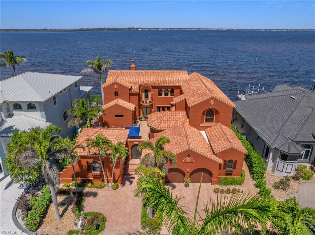 Offered for the first time, this extraordinary custom-built waterfront estate is a rare architectural expression blending Mediterranean style architecture with Spanish hacienda influences, thoughtfully designed by renowned Southwest Florida architect Bud Lawrence and constructed by a highly respected custom home builder. The residence reflects exceptional craftsmanship, intentional design, and a true pride of ownership rarely found in today’s market. Set within a private, gated waterfront community just minutes from Sanibel and Captiva Islands, the home is arranged in a secluded courtyard-style layout with a separate guest casita, creating a resort-like sense of privacy and tranquility. Warm hand-troweled stucco, classic clay tile roofing, graceful arched entries, decorative ironwork, and rich architectural textures define the exterior, blending seamlessly with the timeless character of Florida Mediterranean and Spanish hacienda design. For boating enthusiasts, the brand-new 2023 private dock by Stokes Marine is a standout feature, thoughtfully positioned along the Caloosahatchee River and extending from the expansive rear paver terrace. The dock includes a 14,000-lb boat lift designed to accommodate vessels up to approximately 36 feet in length and 10’6” in width, offering direct access to deep-water river channels, Pine Island Sound, and the Gulf of Mexico, making island hopping, waterfront dining, and world-class fishing effortlessly accessible from your own backyard. At the heart of the home, the private courtyard serves as a central gathering space, complete with a beautifully designed pool and spa, custom tile accents, covered seating areas, and inviting outdoor living spaces ideal for both quiet relaxation and entertaining. Multiple lanais and balconies extend the living experience outdoors, while mature landscaping and palm trees enhance privacy and ambiance. Inside, the home showcases artisan craftsmanship and architectural detail throughout. Extensive custom woodwork, exposed beam ceilings, sculpted ceiling features, carved columns, arched openings, and handcrafted tile accents create warmth, depth, and character across the living spaces. Custom built-ins, niches, and thoughtfully selected finishes further enhance both beauty and functionality. Indoor and outdoor living come together effortlessly, with expansive openings and well-placed glass doors drawing in natural light and framing breathtaking waterfront views from multiple rooms. The home is equipped with impact-resistant windows and doors for peace of mind, along with a large whole-home generator providing reliable backup power. Multiple gathering areas flow naturally from one space to the next, perfect for everyday living, hosting family and friends, or entertaining on a grand scale. Fireside seating areas, open living rooms, and generous entertaining spaces connect seamlessly to the outdoor courtyards, lanais, and balconies.