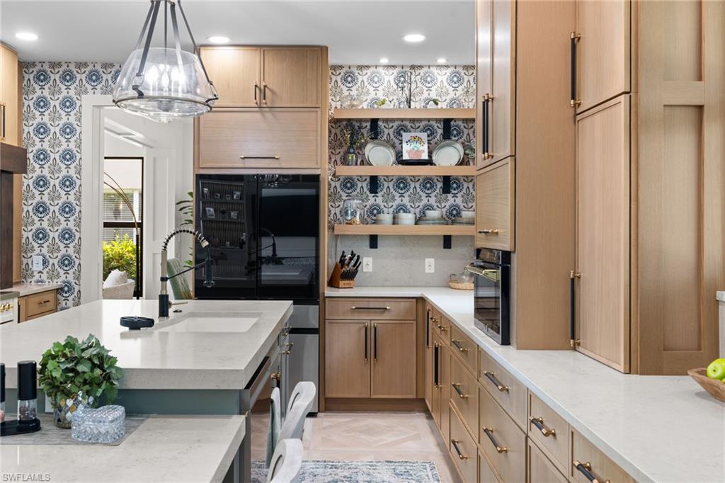 Experience exceptional craftsmanship and modern design in this fully reimagined residence within the highly sought-after Indigo Lakes community. Taken down to the studs and meticulously renovated from floor to ceiling, the home pairs sophisticated finishes with thoughtful functionality throughout. At its center is a striking kitchen anchored by an impressive 11-foot island topped with Royal Taj Mahal quartz. Custom cabinetry, a built-in bar, a 36-inch ILVE Italian six-burner induction range, Brano smart hood, and Samsung smart refrigerator create a space designed for both everyday living and effortless entertaining. Expansive living areas are enhanced by custom millwork, two electric fireplaces, designer chandeliers, LED lighting, and integrated audio, video, and security systems. Oversized 31-by-31-inch solid-body porcelain tile extends throughout the first floor, while the second level features white oak plank flooring. A custom white oak staircase with wrought-iron detailing connects the two levels with architectural distinction. Each bathroom has been fully redesigned with custom tile work and elevated finishes. The spa-inspired primary bathroom offers a freestanding soaking tub and a serene, refined atmosphere. Two laundry rooms, one on each floor, add an uncommon level of convenience. Additional improvements include impact windows and doors, three new hurricane-rated garage doors, an epoxy-finished garage floor, fresh interior and exterior paint, and added attic insulation for improved efficiency. Outside, a private backyard retreat awaits with a heated pool, newly screened enclosure, upgraded paver deck, and new irrigation system. A dedicated theater room completes the residence and may also serve as a flex space, private office, fitness room, or guest bedroom. With virtually every major component replaced, upgraded, or thoughtfully redesigned, this residence offers the rare opportunity to enjoy the quality and finish of a comprehensive luxury renovation without the time and uncertainty of completing one yourself.
