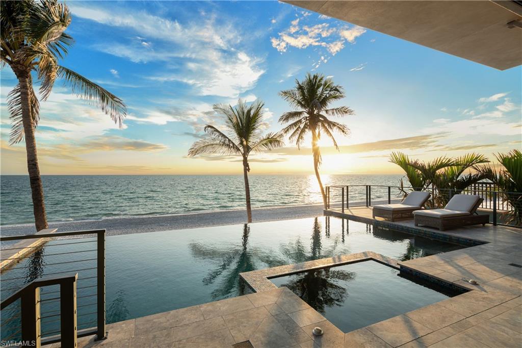 2018-BUILT DIRECT BEACHFRONT MASTERPIECE WITH AN ELEVATED POOL! Enjoy the sugar white sands and turquoise waters of the Gulf as your daily backdrop. Custom-built by the renowned Potter Homes, this coastal contemporary home is thoughtfully designed with only the finest finishes—from rich white oak flooring to soaring coffered ceilings with handcrafted wood paneling. Crafted like a fortress, this home is built with solid concrete block construction, hurricane impact glass, and electric storm shutters. The expansive open floor plan is perfect for entertaining, enhanced by fully pocketing sliders that lead to a RARE, ELEVATED POOL DECK. This spectacular outdoor space includes a sleek infinity-edge pool and spa, a summer kitchen, outdoor fireplace, and pool bath—perfect for seamless indoor-outdoor living with breathtaking Gulf views. Spanning 5,214 square feet under air, this home offers 5 bedrooms, 5 full baths, 2 half baths, and a spacious garage with room for 6+ vehicles. The gourmet chef’s kitchen boasts an oversized quartz island, dual-tone cabinetry in warm espresso and crisp white, an ocean-blue backsplash, and top-of-the-line appliances. The luxurious primary suite is a serene escape with panoramic Gulf views and access to an open-air balcony. It has a spa-like bathroom with a massive walk-in shower with bench seating and multiple showerheads (including a rainfall option), a freestanding soaking tub, and dual vanities. Additional highlights include 2 new HVACs, a private elevator, a wet bar with a wine fridge, electric interior screens, and smart home features (Crestron sound/media/lighting system). Ideally located within walking distance of top beachfront dining and just minutes from Mercato, The Promenade, Waterside Shops, Coconut Point, 5th Avenue, and the International Airport nearby. This home is the pinnacle of beachfront living.