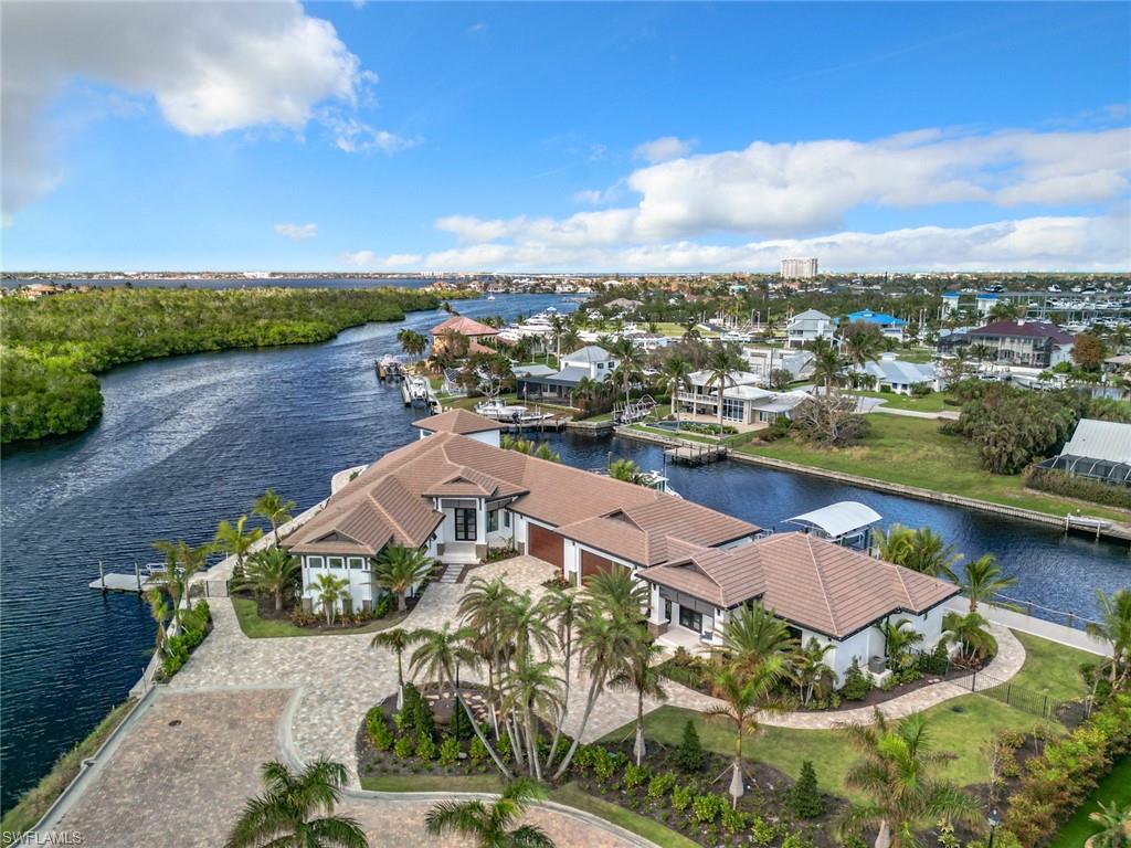 Don't miss this boater's paradise with direct (no bridges) deep water Gulf Access only minutes from the river. 
This one of a kind property features ultimate privacy in this exclusive, gated waterfront community.  Brand new premium construction by award winning builder, Windward Construction, on a near triple corner lot with nearly 500 feet of seawall, all of which has extra elevation to keep you high and dry.  This exquisite smart home features nearly 7000 square feet under air including a massive garage with rear bay doors for ease of transferring supplies to your boat.  A boater's paradise with deep water direct access to the Gulf of Mexico.  Station your yacht on the 100 foot floating dock with ramp and store your tender boat on its own lift.  Utilize the  additional 7,500 lb covered lift for your every day watercraft.  A total of 5 bedrooms with designated full bathrooms and 2 half bathrooms, one of which is accessible from the pool area.  The in law suite with private entrance is an impressive 2 bed, 2 bath alluring space with its own private patio.  A welcoming open floor plan features a great room with a backlit granite wall with built in linear electric fireplace and sublime wood beams on the cathedral ceilings.  The remarkable outdoor area includes a summer kitchen with built in gas grill, expansive seating area including gas fireplace area, a heated infinity edge pool with integrated spa and lengthy shallow walkout.  The spiral outdoor stairwell takes you to a bonus air conditioned room with a breathtaking view which can be utilized in so many different ways.  The elegant shell stone tile flows through the home and beyond the pocket sliders bringing a seamless transition to the expansive outdoor living area. This is a custom built home with the Florida lifestyle very much at the forefront of every aspect of construction and  design including a 1000 gallon propane tank that will operate the Generac home generator for weeks!  Impact doors and windows and dual electric hurricane and insect screens provide added protection to the lanai area.  Located just off McGregor Blvd., minutes from beaches, restaurants, and shopping and only 6 miles from the private airport, Page Field and 16 miles from Fort Myers International. The staging furniture has been removed and the home is ready for quick occupancy.