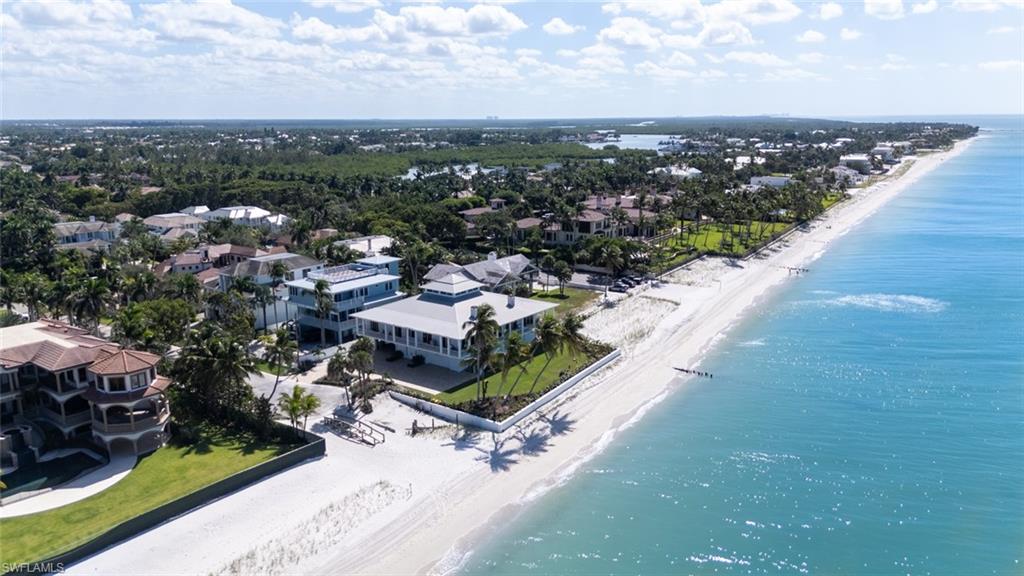 With sweeping, unobstructed views of the beach, this custom-built masterpiece represents a rare opportunity to own an unparalleled beachfront retreat all viewed from the first living level at 20 feet above. Positioned on 135 feet of prime Gulf frontage, this 2015-built property offers breathtaking panoramic vistas that are simply unmatched. Designed to maximize outdoor enjoyment, the residence features a beautiful wrap around porch and an expansive ground-level backyard, perfectly suited for embracing Naples' coveted lifestyle. Inside, the open floor plan with main living area on the second floor showcases soaring ceilings, elegant hardwood floors, and a fresh, coastal aesthetic. The gourmet kitchen, equipped with premium appliances and sleek countertops, flows seamlessly into the spacious living area, offering uninterrupted Gulf views—the true centerpiece of the home! Additional highlights include impact-resistant windows and doors, a wraparound seawall, an elevator, three fireplaces, and an expansive garage accommodating eight or more vehicles. New Aluminum roof as of June 2026! Ideally situated just minutes from Naples' world-renowned dining, shopping, and cultural attractions, and eligible for Port Royal Associate Membership, this property sets the standard for beachfront luxury living. Walking distance to the Port Royal Club opening 2026!