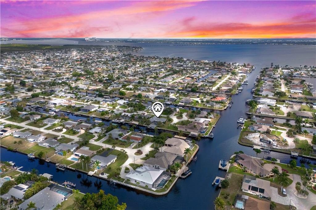 DIRECT BOAT ACCESS – MINUTES TO OPEN WATER! Nestled on a quiet cul-de-sac in the highly sought-after Gold Coast waterfront community, this beautifully maintained 3-bedroom, 3-bath pool home sits on an oversized direct-access lot with no bridges and quick Gulf access. Boating enthusiasts will appreciate the private dock with two boat lifts, complemented by a waterside tiki hut perfect for relaxing while enjoying peaceful canal views. Inside, the home features tile wood-look flooring throughout, upgraded lighting fixtures, and custom molding with architectural detailing. The updated kitchen offers wood cabinetry, granite countertops, stainless-steel appliances, and a built-in wine cooler, flowing seamlessly into the dining area highlighted by a wood-accent ceiling. Experience true Florida outdoor living with a raised screened lanai, a resort-style pool with sun shelf/ledge, and a fully equipped outdoor kitchen with built-in grill. A convenient pass-through to the sunroom enhances seamless indoor-outdoor connectivity. The primary suite provides a private retreat with a spa-inspired bathroom featuring a large walk-in shower, double vanity, and an expansive walk-in closet complete with a separate makeup vanity. One of the guest bedrooms is an ensuite, offering added comfort and privacy, while the third bedroom is ideal for guests or a home office. Additional features include a spacious garage with room for a golf cart, recreational toys, or extra storage, mature tropical landscaping, continuous curbing, and a central location close to bridge access, dining, shopping, and major routes. This exceptional waterfront home offers the perfect blend of location, upgrades, and an unmatched boating lifestyle.