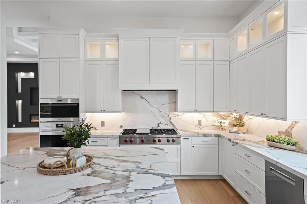 Perfectly positioned in one of Naples’ most desirable coastal neighborhoods, 623 Park Shore Drive offers the rare combination of luxury new construction, an active lifestyle and private beach access. Located just moments from The Village Shops on Venetian Bay and the Park Shore Private Beach Park, this residence places world-class dining, boutique shopping, sunsets and the Gulf of Mexico within easy reach. This newly constructed concrete block residence was designed with quality, comfort and long-term peace of mind at the forefront. The home features Andersen 400 Series hurricane-impact windows and Velocity sliders, motorized lanai screens, hurricane shutters, a 27-kilowatt whole-house Generac generator and a 1,000-gallon propane tank. Inside, refined finishes include French oak wood plank flooring, solid-core interior doors, elevated ceiling details and a dramatic great room with a custom entertainment wall and electric fireplace. The kitchen makes a strong luxury statement with an oversized book-matched quartz island, WoodHarbor bevel shaker soft-close cabinetry, Wolf appliances, a Bosch dishwasher, Sub-Zero refrigeration and an oversized picture window that brings natural light into the heart of the home. A wet bar with an icemaker, wine cooler, glass shelving and custom cabinetry adds to the home’s entertaining appeal. The private primary suite is light-filled and sophisticated, offering dual walk-in closets, a spa-inspired bath with dual quartz vanities, a freestanding soaking tub, an oversized seamless walk-in shower, a custom quartz shower bench and wood-wrapped mirrors with sconces. Three additional guest bedrooms are en suite, each finished with high-end cabinetry, walk-in showers with decorative tile details and built-out closets. Outdoor living is a major highlight. The covered lanai features marble pavers, a full outdoor kitchen with an Artisan grill and refrigerator, custom weatherproof cabinetry, a gas fireplace, recessed TV space, shelving and motorized retractable screens. Beyond the lanai, the saltwater pool, spa, three water features, sunken gas fire pit with wraparound seating, fenced backyard and large grassy side yard create a true private resort setting. Additional features include an expansive laundry room with custom cabinetry and raised quartz folding counters, a dedicated study or fifth bedroom with a closet off the lanai, lush landscaping with lighting and irrigation and an oversized three-car garage with 10-foot doors, epoxy floors and 14-foot ceilings designed to accommodate car lifts. Just minutes to Venetian Bay, Park Shore’s private beach access, Waterside Shops, downtown Naples and the best of the Gulf Coast lifestyle, this residence delivers the best of new construction living in the heart of Park Shore. Furniture design packages available upon request.