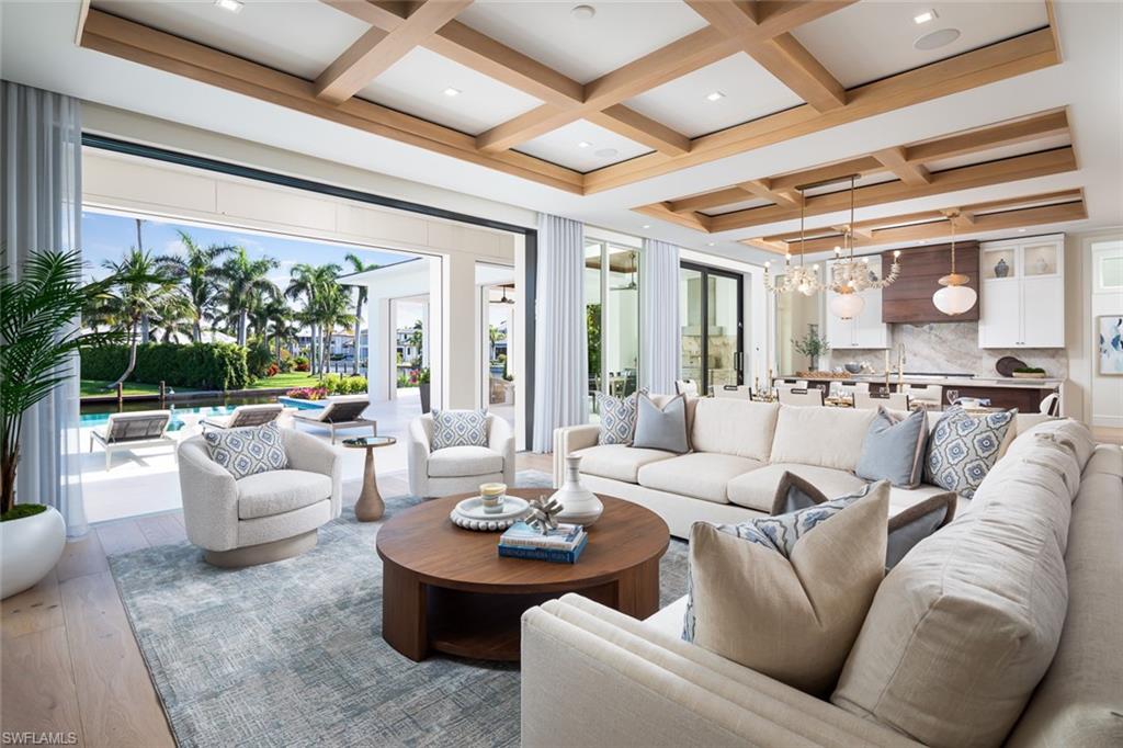 Showcasing light and breezy seaside-inspired aesthetics complemented by warm natural wood tones, this newly constructed masterpiece by Wilbrett Construction Company is a testament to exceptional craftsmanship.  Designed with sophistication by Kukk Architecture and finished with the exquisite touches of Freestyle Interiors, this home spans approximately 6585 square feet of meticulously planned living space, adorned with luxury features at every turn.  Step into a grand great room where intricate ceiling details add a touch of artistry and seamlessly flow into the chef's kitchen complete with custom cabinetry and a well-appointed butler's pantry.  Adjacent to this central space, a wet bar and temperature controlled wine cellar perfectly complement a spacious study, offering a refined retreat with custom cabinetry that harmonizes functionality and elegance.  The main-floor primary suite offers tranquil water views and a spa-inspired bath featuring a freestanding soaking tub and a walk-in shower.  Upstairs, four generously sized ensuite bedrooms encircle a central living area, which includes a wet bar and access to an extended balcony that captures spectacular wide water vistas.  Outdoor living is a dream come true with a resort-style infinity-edge pool, soothing spa, and sun shelf, surrounded by a covered loggia outfitted with remote controlled screens and shutters.  A stone-clad fireplace creates a cozy ambiance, while the outdoor kitchen makes hosting gatherings effortless and enjoyable. Ideally situated on the waters of Egret Channel, with its prime location at the intersection of Heron Cove and Gull Cove, the property takes full advantage of sweeping water views.  Boating enthusiasts will appreciate the deep-and wide water frontage, ideal for navigable access.  This serene setting is also just moments from Naples' pristine white sandy beaches and the shops and restaurants of Third Street south.  This thoughtfully designed residence embodies the quintessential Florida lifestyle, offering a rare blend of elegance, comfort, and functionality.