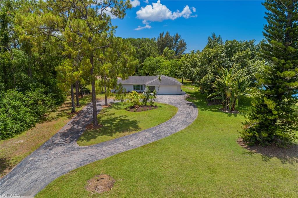 MOVE IN READY and thoughtfully updated, this 3 bedroom, 2 bathroom home is situated on an expansive 3.19 acre homesite with a canal running along the entire right side of the property. Major improvements have already been completed, including a new roof in 2018, impact glass windows installed in 2019, fresh custom interior and exterior paint, a remodeled kitchen with white shaker style cabinetry and granite countertops, and an updated primary bathroom featuring a walk in shower with a glass enclosure. The freshly painted exterior and recently refreshed garden beds enhance the home's curb appeal, while the oversized property offers exceptional space and endless possibilities to enjoy the outdoors. Inside, quality laminate flooring extends throughout the main living areas, creating a clean and cohesive look. Large windows fill the home with an abundance of natural light, giving the interior a bright and inviting feel. The spacious primary suite features a walk in closet and an updated bathroom with a walk in shower and glass door. Both guest bedrooms are generously sized and are conveniently located near the guest bathroom. The living room and dining area open directly to the large screened lanai, creating an ideal space to enjoy the Florida lifestyle with plenty of room for outdoor seating and dining. An inside laundry room with a utility sink adds everyday convenience, and the long circular driveway provides ample parking along with an impressive approach to the home. Combining significant updates, a spacious floor plan, and over 3 acres of land in a desirable Naples location, this property is ready for its next owner to move right in. Conveniently located in Golden Gate Estates, this property offers the space and privacy of acreage living while remaining close to everyday conveniences. Shopping, dining, grocery stores, schools, parks, and golf courses are all within easy reach, with quick access to both Golden Gate Boulevard and Immokalee Road for travel throughout Naples. Downtown Naples, world renowned Gulf beaches, Mercato, and multiple public boat ramps are all just a short drive away, allowing you to enjoy the best of Southwest Florida while still having plenty of room to spread out at home.