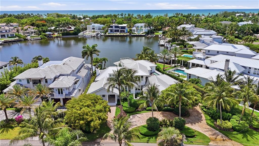 A boater’s paradise in the heart of Aqualane Shores on prestigious 4th Street South, showcasing wide water views across Aqua Cove and direct Gulf access along one of Naples’ most coveted waterways. This exceptional waterfront estate features 4 spacious bedrooms plus a private office, 4 full baths, 2 half baths, and a thoughtfully designed living space created for indoor-outdoor living. Fully pocketing glass doors connect the gourmet kitchen and expansive great room to the covered lanai, pool, spa, and waterfront areas, creating effortless flow for entertaining and everyday living. The kitchen is appointed with premium appliances, custom cabinetry, designer finishes, and an oversized island ideal for gatherings. The luxurious primary suite features tranquil waterfront and pool views, dual custom walk-in closets, freestanding soaking tub, oversized walk-in shower, paired marble vanities, skylight, outdoor shower and a private terrace with motorized screens. Additional highlights include a whole-house generator, standing seam metal roof, 3-car air-conditioned garage with room for lifts, motorized lanai screens, wide-plank Acacia walnut flooring, tray and coffered ceilings, Lutron lighting system, Sonos surround sound, and Andersen impact-resistant windows and doors. Resort-style outdoor amenities include a gas-heated saline infinity-edge pool and spa, expansive lounge areas, and a completely rebuilt ‘grandfathered’ boathouse with covered boat slip, lifts, and rooftop sun deck. Ideal for enjoying the Naples waterfront lifestyle and breathtaking sunset skies. Built by Hemmer Construction, designed by Jeff Harrell Architects, and finished by LDL Interiors, this residence blends sophisticated architecture with refined finishes and exceptional craftsmanship. Cruise to the Gulf or walk to the beach in minutes while enjoying close proximity to fine dining, luxury shopping, and downtown Olde Naples.