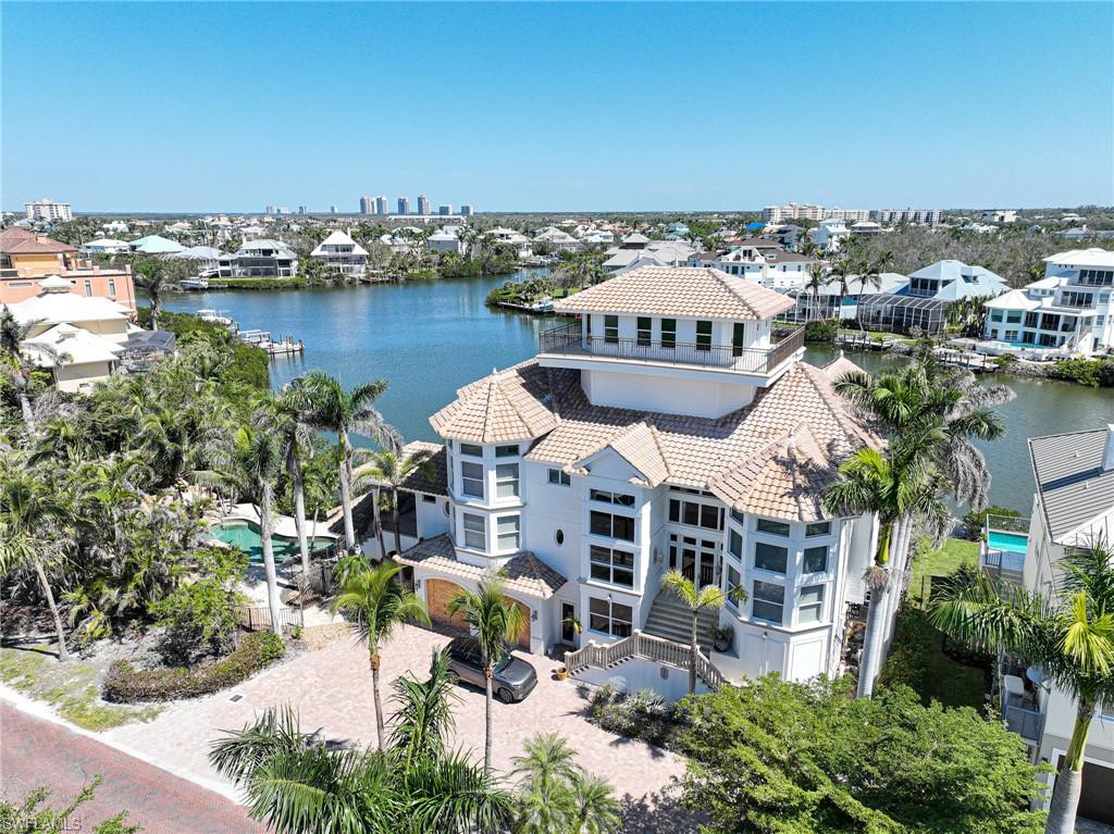 This 4 story Barefoot Beach Bayside home offers the ultimate Florida lifestyle including nearly 6,000 sq ft of AC space & over 14,000 total sq ft of indoor/outdoor living all sitting on a double sized bayfront lot w/resort style tropical pool with grotto, waterfall & slide, covered bar & summer kitchen, premier boating with a large boat dock with 20,000 lb lift & double jet ski dock with quick direct Gulf access with no bridges, beach access across the street, 5 bedrooms 4.5 baths wide bay views from nearly every room & deck, a 4th floor 360 deck offering forever views of the Gulf and bays. Features include two story great room w fireplace & adjacent to the gourmet kitchen w professional appliances including double wall ovens and a Wolf gas cooktop and multiple dining options. The master bedroom has a sitting area & gas fireplace and large master bath. Bonus/family room on 4th floor offers wood lined ceilings & stunning views. Barefoot Beach is Guard gated & 24 hour patrolled. Unfinished lower level areas including garages and bar area of the home were flooded in Ian. Property was dried, drywall removed where required and swimming pool repaired. Remaining repairs by Buyer.