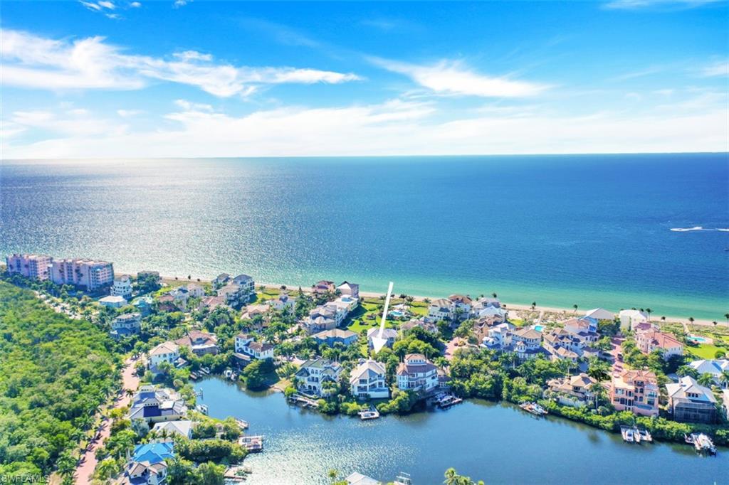 Behind the guard-gated waterfront enclave of Barefoot Beach, 232 Barefoot Beach Blvd is sublimely situated between the Beach and Bay. This masterpiece offers breathtaking Bay views through floor-to-ceiling retractable glass doors. Brimming with refined elegance & custom designer touches, this estate boasts 5 bedroom suites, a 3 car garage, elevator & a private boat dock/lift.  The gourmet kitchen features an enormous island, stunning quartz counters, Thermador & SubZero appliances, double wall oven, an adjacent dining area & a wet bar with Virtrazzo counters, martini-fridge & dual temperature SubZero wine cooler. An exceptional outdoor oasis boasts seamless indoor-outdoor entertaining with a glistening pool/spa, ample seating, and a summer kitchen with gas grill. Upstairs, 4 private suites offer a tranquil retreat for your guests. The lush landscaping provides a tropical setting with lime & lemon trees. Additional features include Lutron lighting, engineered Maple hardwood floors, security Ring doorbell with all-door security sensors, electric screen/shutters, bonus room/flex space with wet bar, massive top-floor lanai. Just a stone's throw from the beach, LUXURY awaits you here!