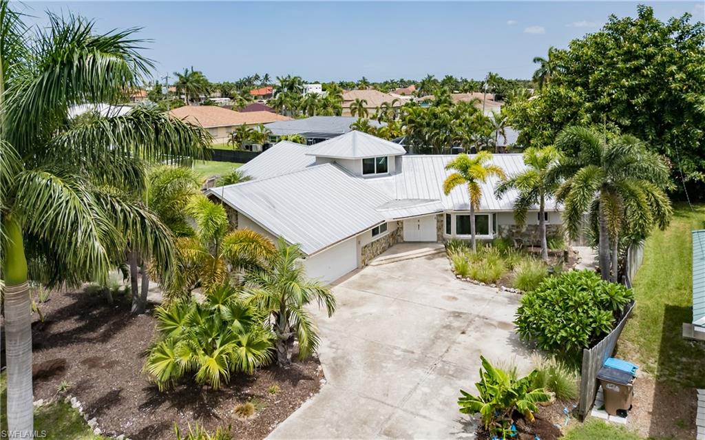 Welcome to your dream home in the Cape Coral Yacht Club Neighborhood! This exceptional residence that sits on an oversized lot offers a functional and unique floor plan that sets it apart from the rest. Spanning an impressive 2,237 square feet, this home features three spacious bedrooms, two baths, and a versatile den/loft on the second floor, perfect for an office, gym, or an additional guest room.

Step outside to discover your personal paradise, complete with a large screened, enclosed pool and a separate outdoor bar and Tiki lounge area, ideal for entertaining friends and family or enjoying quiet evenings.

This home is equipped with all-new hurricane impact windows and sliders, ensuring peace of mind during stormy weather. A durable metal roof, installed in 2010, and a privacy fence added in 2017 enhance both safety and aesthetics. Other major upgrades include a new A/C unit installed in 2025, whole house water filtration system, and ADT security system.

The split floor plan offers endless possibilities for organizing your living space. With two inviting living rooms, two dining areas, and a flexible space that could easily accommodate a pool table, you’ll have the freedom to customize the layout to suit your lifestyle.

This property is a must see! Schedule your private tour today and experience the charm and versatility this home has to offer.