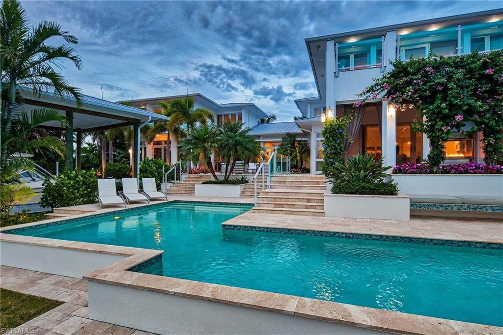This is PERFECTION! ~Step into the grand foyer of this contemporary masterpiece and immediately you are drawn to the picture perfect outdoor space which boasts a covered boat house w/ a 27K lb lift, a 42' "L" shaped lap pool & spa, a brand new 2019 seawall, amazing sitting areas surrounded by beautiful landscaping, a covered screened lanai with an outdoor fireplace, and a convenient grill area. All 5 bedrooms are super spacious w/ private balconies; and the Luxurious Master Suite has a 24' balcony overlooking the intersecting canals which provide a long water view and a slice of the bay where you will experience endless sunsets. The "media" room features a bar & is sizable enough to accommodate a pool table! The kitchen is every chef's dream, with a HUGE walk-in pantry and only the finest appliances and finishes. There are two oversized 2-car garages to fit 4 vehicles easily. There is not another home presently on the market that has 5 bedrooms, 4 car garage parking, a king-size homesite & a boat house for this price! The attention to detail is beyond reproach! The photos tell a story, but you really must see this special home in-person to fully appreciate the quality and design.