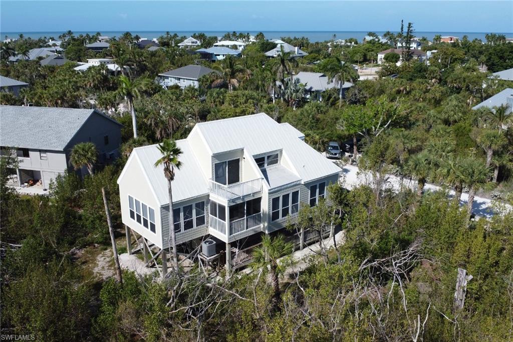 Nestled within the highly sought-after Gulf Pines community on beautiful Sanibel Island, this elevated 3-bedroom, 2-bath home offers the perfect blend of privacy, nature, and timeless island charm. Surrounded by lush native vegetation and adjacent to a protected wildlife area with no future neighboring development, this property delivers the peaceful “Old Florida” lifestyle Gulf Pines is known for. Spacious homesites, winding paths, and a serene natural setting create a true island retreat just moments from the Gulf.

Residents of Gulf Pines enjoy exceptional amenities including community swimming pool, tennis courts, and a beautifully maintained clubhouse perfect for social gatherings and events. A private deeded beach path leads directly to one of Sanibel’s most breathtaking stretches of shoreline, where world-famous shelling, unforgettable sunsets, and the soothing sound of the Gulf become part of everyday life. Here, mornings are spent biking scenic island trails, afternoons relaxing on the beach, and evenings immersed in nature’s beauty.

Filled with cheerful natural light, the home features soaring vaulted ceilings, expansive windows, and a spacious living room that flows seamlessly to multiple porches and screened outdoor spaces ideal for entertaining or simply enjoying the tropical surroundings. Thoughtful upgrades throughout include new flooring and interior paint, recessed lighting, cedar plank accents, tongue-and-groove patio ceilings, and beautifully updated finishes. The dining area is enhanced by a wet bar and wine cooler, creating the perfect setting for entertaining. The bright open kitchen features new white cabinetry, quartz countertops, stainless steel appliances, and modern lighting.

The layout is designed for both comfort and privacy, with two guest bedrooms and a beautifully remodeled guest bath with high-end finishes located on the main level. Upstairs, the private primary suite feels like a tranquil escape, featuring lofted ceilings, two closets, a sliding barn door, abundant natural light, and its own private balcony overlooking the lush surroundings.

Additional features include a metal roof, covered carport, downstairs laundry area, and classic beach-home character throughout. Whether you are searching for a full-time residence, seasonal getaway, or investment opportunity, this exceptional Gulf Pines home captures the very best of the Sanibel lifestyle.