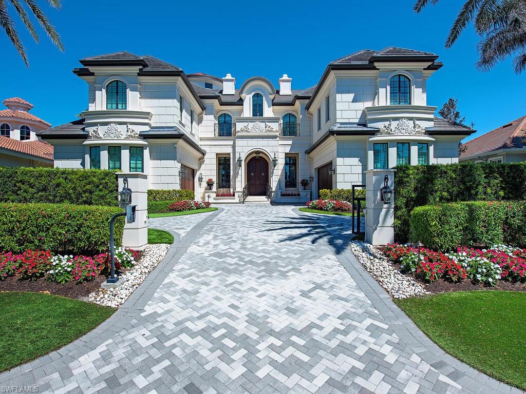 $1,500,000 Price Reduction since March 2nd 2026. An extraordinary opportunity to own a one-of-a-kind waterfront estate in the heart of Park Shore. Majestically positioned behind a gated and walled entrance, this architecturally distinctive residence is defined by its quoined white stucco façade, dark-trimmed windows and doors, and timeless copper accents—setting it apart from all other newer homes in the area.
Upon entry, you're greeted by gleaming marble floors, crisp white walls adorned with detailed moldings and volume ceilings with intricate finishes in white, gold leaf, and rich wood tones. The dramatic two-story living room stuns with a floor-to-ceiling limestone fireplace, a sweeping circular marble staircase, multiple crystal chandeliers, and a custom 3-sided glass wine vault—an entertainer’s showpiece. All flooring material either marble, tile, wood, no carpet.
The open-concept great room and chef’s kitchen are ideal for both daily living and grand-scale entertaining. Designed to flow seamlessly to the outdoors, the space opens to an expansive covered lanai complete with a fireplace, grill area, fire bowls, and a stunning negative-edge pool and spa. All of this is framed by panoramic water views and leads to the home’s 94-foot dock, which features a stone deck with water-viewing panels—perfect for boating enthusiasts, sun bathers and waterfront living.
Offering five en-suite bedrooms, including dual primary suites—one on the main level and another on the second floor. Each primary suite is designed as a private retreat, with its own luxurious bathroom and oversized custom walk-in closets. The upper-level suite boasts two separate spa-inspired baths and extravagant dressing room. Three additional guest suites ensure comfort and privacy for family and visitors alike.
Additional features include a second-floor lounge, private den, oversized pantry, three separate laundry rooms for convenience, a four-car garage, and a full-house generator. The home is equipped with a fully integrated Control4 smart home system, allowing seamless control of lighting, audio, window treatments, and more from anywhere.   Improvements in 2023 & 2024: repaint of entire exterior, refreshed landscaping and new whole house water purification system. This exceptional residence combines elegant design, luxurious finishes, and the best of Naples waterfront living—all within minutes of the beach, Venetian Village, and the renowned shopping and dining of downtown Naples.