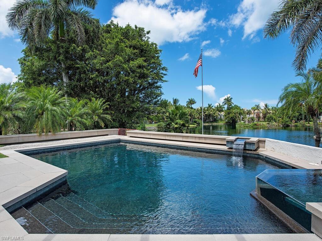 NEW ROOF AND SKYLIGHTS IN 2025. Enveloped by mature trees, this nearly 3,100 sq. ft. Port Royal residence is ideally nestled on serene Half Moon Lake and a mere few minutes' walk to the soon-to-be newly constructed Port Royal Club. The lovingly maintained home was designed by renowned architect Kasimir Korybut and includes a main level with spacious living areas and soaring ceilings, two en-suite bedrooms with lake views, a half bath, and a modern custom kitchen.  Floor-to-ceiling sliders open to extend your living to the outdoors, where residents are able to enjoy the copious amounts of varied wildlife, as well as enjoy a luxurious saltwater pool / spa, outdoor shower, and kitchen.  By means of a spiral staircase, the second level consists of a spacious bedroom toting sliders that open to a private balcony, as well as a lavish bathroom. Auto enthusiasts will delight in having a fully tiled, air-conditioned garage with plenty of space.  Port Royal is a world-class community with close proximity to all that Naples has to offer including sugar sand beaches, shopping, & dining.