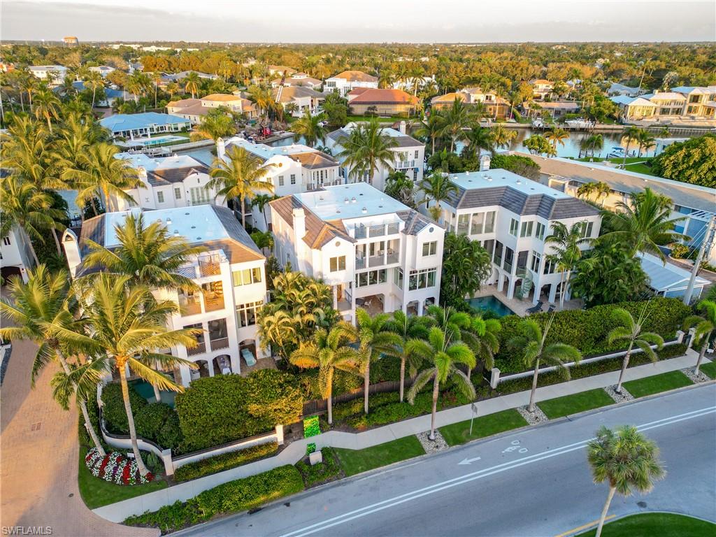 Welcome to Casamore, an exclusive community offering tranquil living in a picturesque setting. This stunning 4-bedroom plus den residence is a masterpiece of modern design, featuring premium finishes throughout. White oak hardwood floors, impact windows, an all-level elevator, and tasteful coastal furnishings create an inviting atmosphere. The gourmet kitchen is equipped with top-tier appliances, a 6-burner gas stove, sleek Brookhaven cabinetry, exquisite Taj Mahal quartz countertops, and a spacious walk-in pantry. The luxurious primary suite boasts dual bathrooms and closets with custom-built cabinetry, plus a private covered balcony for serene relaxation. Head up to the private rooftop terrace for panoramic Gulf views, perfect for entertaining or unwinding. The outdoor spaces are designed for ultimate enjoyment, with a large sitting area featuring a fireplace and grill, a private pool with a spa, an outdoor shower, and direct access to your private boat dock. A gated beach entrance adds to the allure. Just steps from the beach, this home captures the essence of coastal luxury living in Naples. Single Family Residence-Land Condo.