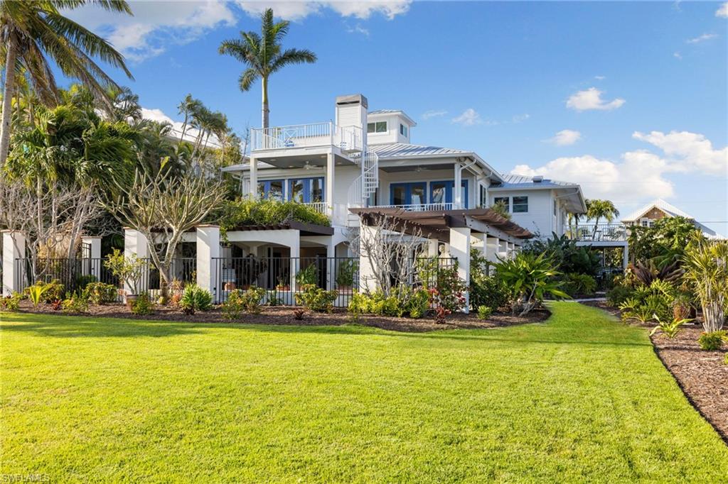With unobstructed views of the bay, perfectly framed by the tropical landscape, this residence embodies the essence of waterfront living. Upon entering the main level, you will be greeted by an abundance of natural light and vistas complimenting the fireplace in a harmonious blend of coastal and classic design. Entertain family and friends in the formal dining area or the main level balconies overlooking your backyard as dolphins swim in the background. The kitchen boasts views of the bay and offers plenty of cabinet and counterspace, a gas range and a wet bar that connects the kitchen to the family room. The primary quarters offer two walk in closets and a spacious bedroom surrounded by mature landscaping that integrates with the natural beauty of the surroundings. The well appointed guest bedrooms, one on the main level and the other on the first floor, award your guests with privacy. On the first floor you'll find a separate sitting room, a den (which the owners used as an exercise room) and a laundry room with an extra refrigerator and sink. From the office and recreation rooms you can step outside onto the expansive patio, where the beauty of coastal living truly comes to life. Sip cocktails as you watch boats glide across the bay, or indulge in alfresco dining under the pergola covered in blooming flowers. This waterfront setting offers endless opportunities for outdoor recreation, from kayaking and paddleboarding to fishing and birdwatching. The boating community of St. James City is conveniently located a short boat ride away from the Sanibel Causeway and beaches to the south and to the north, through Pine Island Sound, to the world famous Cabbage Key, Useppa Island, and Boca Grande pass. Whether appreciating some of the most pristine natural habitats in SWFL, sport fishing for tarpon or bar hoping by water, the options are endless