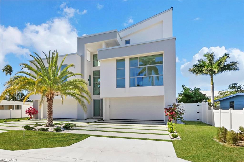 There are homes designed to impress, and then there are homes designed to endure. 
This is unmistakably the latter. 

From the moment you arrive, the presence is calm, intentional, and confident. A mature Sylvester Palm anchors the entry, setting the tone for a residence that feels both rooted and forward-looking. This is modern coastal living for someone who values beauty and foresight. 

Built by New Era Construction and designed by Harrell & Co. Architects, this home was engineered with uncommon rigor; 55 pilings installed prior to foundation, more structural engineering than required, and materials selected not just for style, but for longevity. This is a home built to withstand the worst, so everyday life feels effortlessly secure. 

Inside, natural light pours through custom ES- impact resistant windows and doors, illuminating soaring ceilings that rise from 12 to over 20 feet in the main living spaces. The aesthetic is warm modernism: a thoughtful blend of tile and Legno Bastone wide-plank birch wood flooring, solid wood stair treads, and sleek glass handrails that create continuity across all three levels. Every door is solid-core and custom, reinforcing the quiet, insulated luxury you feel as you move through the home. 

The main living floor is anchored by quartz countertops throughout, a chef’s kitchen that balances performance and polish, and details that true design enthusiasts notice. Solid wood cabinetry and a hidden walk-in pantry keeps the kitchen visually serene while Linear diffuser vents offer a clean, architectural ceiling line. 

A dramatic spiral staircase leads you upward, complemented by a glass-enclosed elevator servicing all three floors ... both sculptural and practical. Marble-clad bathrooms elevate daily rituals into spa-like moments, while every space feels purposeful and refined. 

Step outside and the lifestyle truly unfolds. The backyard is a private coastal retreat featuring a custom Pebble Crete swimming pool with sun shelf, a raised six-person spa, PVC composite decking with Resin Eco pilings and a 13,000 lb boat lift, thoughtfully built above the seawall. Not to mention, expansive water views and unforgettable sunsets. 

Practical luxury continues with a standing seam aluminum roof, a concrete seashell driveway, irrigated Zoysia lawn, custom landscaping, and an oversized garage accommodating up to six vehicles. Truly a rare find for boating and car enthusiasts alike. 

Located just minutes from downtown Naples, 5th Avenue, white-sand beaches, and world-class golf, this is a home for someone who wants proximity without compromise, luxury without fragility, and a residence that feels as intelligent as it is beautiful. 

1798 Holiday Lane isn’t just a new construction home. 
It’s a statement of foresight, resilience, and refined Naples living—designed for a life well lived, and built for everything that comes next.