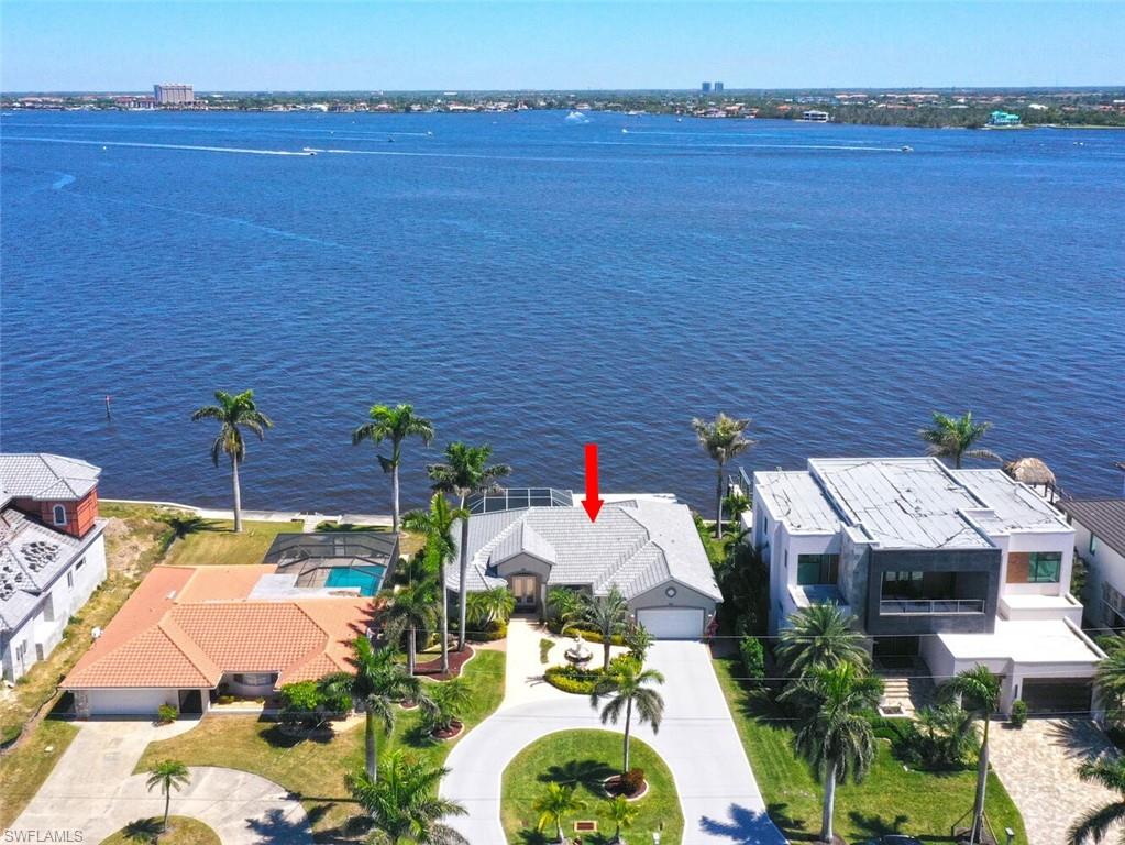 This stunning riverfront home is located on a quiet, residential street in the much sought-after Yacht Club area of Cape Coral. This furnished 3 bed + den, 2-1/2 bath house sits on a double lot w/unobstructed, panoramic views of the one-mile-wide Caloosahatchee River. This home sat high & dry during the hurricanes without any interior water intrusion. Owner's flood insurance at $3K is transferrable to buyer. A new tile roof, a 3-tier water fountain, a circular drive & stamped concrete complete the curb appeal of this majestic estate home. The moment you walk thru the front door you are struck by the towering ceilings & breathtaking river views from the massive great room which has a wall of pocket sliding glass doors providing you w/the opportunity to combine indoor & outdoor living spaces seamlessly. Off the great room is an open den w/views of the river. Almost every room in the home captures this peaceful & relaxing sight as well as the spectacular sunrises! Owner's suite takes up the entire left side of the house for total privacy w/sliders leading out to the lanai to enjoy the river. Spacious owner's ensuite bathroom includes a double shower, large walk-in closet, garden tub & dual sinks. This split bedroom plan has 2 additional bedrooms located on the opposite side of the home that share a bathroom w/dual sinks. The gourmet kitchen is a dream layout w/new granite countertops, tile backsplash & all new stainless-steel appliances. Cook in the kitchen, sit at the breakfast bar or at the dining room table & reap the benefits of the same exhilarating river views. The new substantially built 1200sqft screened lanai w/picture screen provides comfort in any weather. Entertain your guests under the covered space & by the newly refurbished 30x15, 8800-gallon saltwater pool w/solar & electric heat. You will enjoy countless hours lounging on the captain's walk watching birds, dolphins, manatee searching for food & boats sailing by along the protected no wake shoreline. A two & a half car garage w/new electric garage door & epoxy floor provides ample storage space. Your pet, if you have one, will enjoy the decorative fenced-in backyard. The meticulously manicured, lush landscape is the envy of this friendly riverfront neighborhood. There are many extras that come with this house: tile & luxury vinyl flooring thru-out, water softener & reverse osmosis systems, new gutters & downspouts, AC (2024) & more! This home is a short 13-minute walk from the Cape Coral Yacht Club & beach which is undergoing a multi-million-dollar renovation. It includes an expanded beach, 2 new pools, a newly constructed restaurant, a protected marina w/boat docks & a gas pump on the pier. The location is stellar w/plenty of places to shop, eat & enjoy the Florida sunshine only minutes away! Don’t miss the opportunity to call this magnificent riverfront residence your primary home! Also, perfect as a vacation rental or second home! THE LOT ALONE IS VALUED AT THE PRICE OF THE HOUSE!