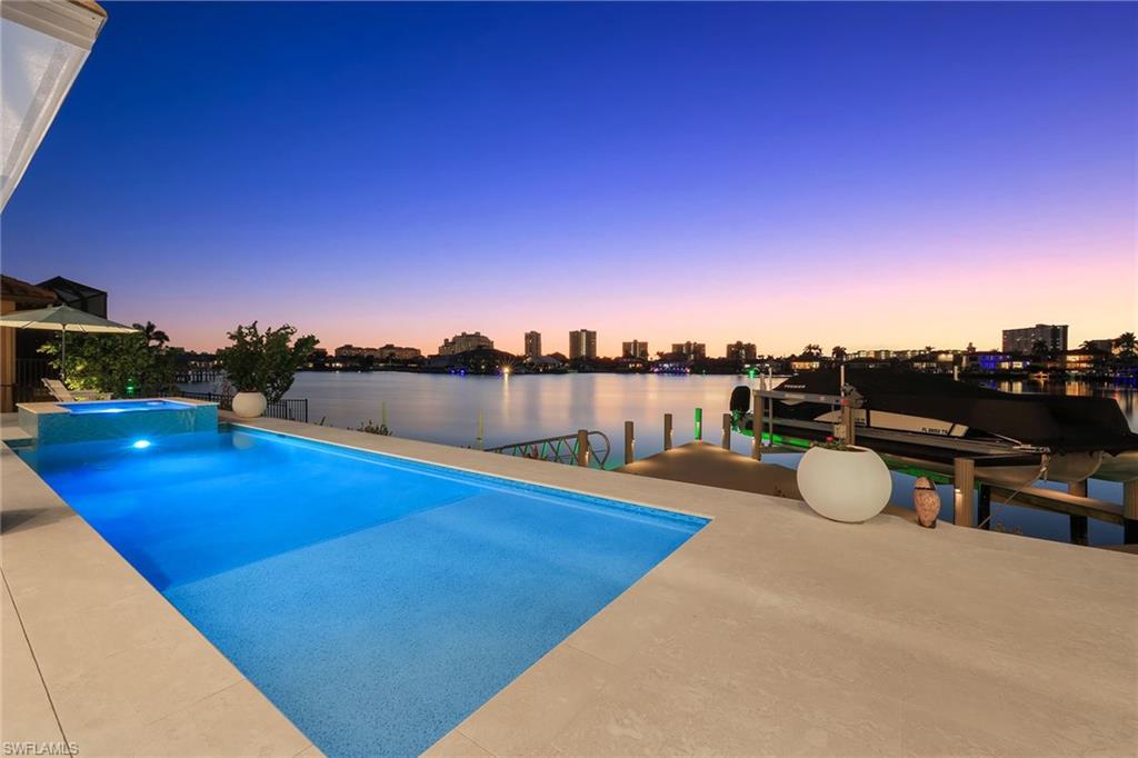 Welcome to this magnificent five-bedroom plus den, 5.5-bath home, in a serene setting with beautiful bay and wide water views. Built in 2023, this home sprawls over 4,100 square feet under air and offers a harmonious blend of luxury, comfort and modern amenities. This furnished decorator home boasts an open-concept design, creating a light and bright atmosphere ideal for relaxation and entertainment. The great room flows seamlessly into the dining area and gourmet chef's kitchen, making it an ideal space for gatherings. The kitchen is a culinary enthusiast’s dream, featuring Thermador appliances, gas stove, walk-in pantry, quartz countertops, breakfast bar and custom cabinetry. Each of the five spacious bedrooms is en suite, offering privacy and convenience for family and guests alike. The primary suite is a retreat, complete with an office area. Additional highlights include hardwood engineered floors, Tray and coffered ceilings, two wet bars, Hunter Douglas blinds, impact glass windows and doors, 500-gallon propane tank, two water heaters, upstairs loft with private balcony, and spacious laundry room equipped with two washers and two dryers. Designed to maximize outdoor living, this residence features a spacious and stunning outdoor area equipped with pool, spa, gas fireplace, summer kitchen, electric shutters and screens. Enjoy alfresco dining as you take in the breathtaking sunsets and gorgeous views. For boating enthusiasts, this property includes a dock with a 14,000-pound lift, making it easy to explore the surrounding waters. The three-car garage and circular drive provide ample parking and storage options. This home shows like a model and is filled with numerous top-quality finishes throughout, ensuring a luxurious living experience. With its prime location and stunning views, this exquisite home offers a unique opportunity to experience the best of waterfront living. Don't miss your chance to own this extraordinary property today.
