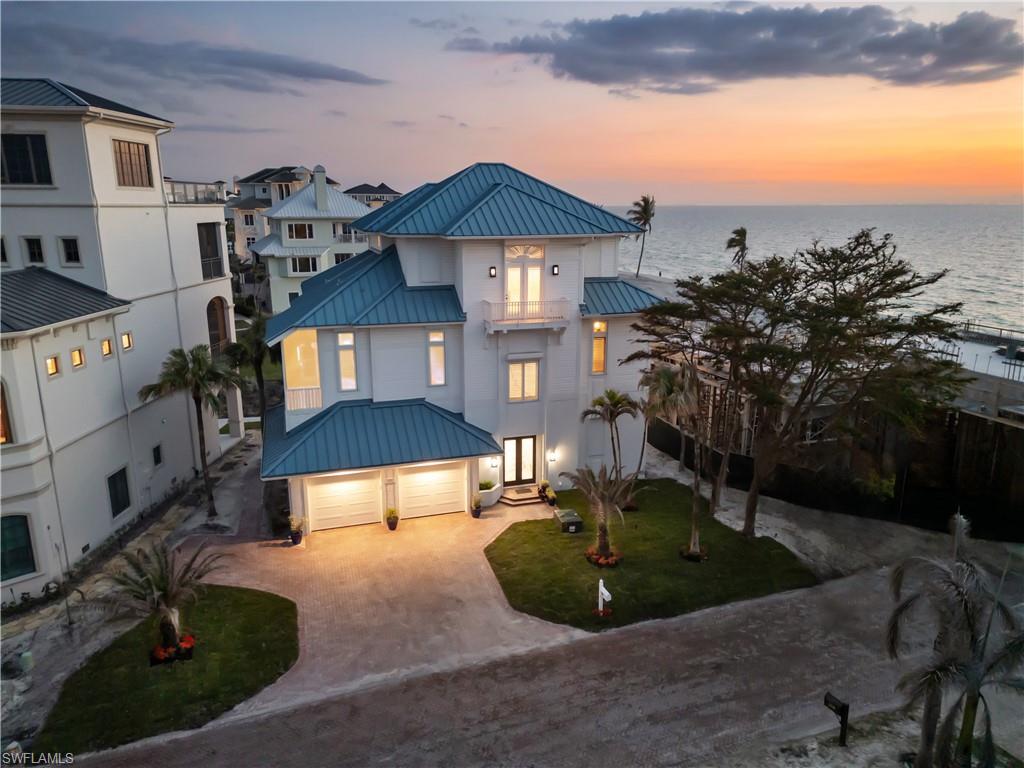 Stunning estate with breathtaking Gulf views in the highly coveted Beach Gardens of North Naples’ Barefoot Beach Community. This remarkable residence offers unparalleled views of pristine sugar sands and the turquoise waters of the Gulf, with private beach access right at your doorstep. This second position home offers coveted Southwestern rear exposure, providing gorgeous natural light throughout the day and stunning sunset views in the evening. This 4 bedroom + a den, 3.5 bathroom coastal retreat boasts hurricane impact windows and sliders, electric hurricane shutters, a private elevator, soaring ceilings, tile flooring, and versatile ground-level flex space. The gourmet chef’s kitchen showcases beautiful coffered ceilings, white cabinetry, granite countertops, an eat-in area, and a breakfast bar for casual dining. The open-concept layout allows for a seamless flow, with a spacious living room and a formal dining area with a domed ceiling and a charming fireplace. Step outside to the second-floor wraparound screened lanai offering a direct west and southwest view, where sweeping views of the Gulf and unforgettable sunsets await. The luxurious primary suite serves as a private retreat, featuring access to its own lanai, dual walk-in closets, a wet bar with a beverage cooler, and a spa-like bathroom with dual vanities, a frameless glass shower, and a separate jetted tub. The Beach Gardens community has undergone a stunning transformation, featuring lush landscaping and a resort-style pool. Optional membership to the exclusive "Club at Barefoot" provides access to tennis, two restaurants, beachside food and beverage service, and more. Conveniently located near fine dining, RSW Airport, Mercato, and Waterside Shops, and just 15 miles from the renowned Fifth Avenue in Naples, this home is a true gem in the heart of Barefoot Beach.