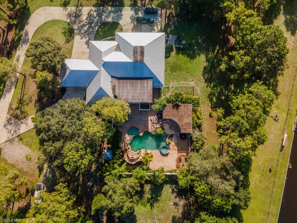 Welcome home to your peaceful and private oasis! 3240 70th St. SW is a beautifully renovated home on over 3.5 acres, just 15 minutes from downtown Naples. This 4 bedroom, 3.5 bath home has an attached 1/1 apartment, complete with a living room and full kitchen. The owner has updated the home with natural walnut flooring throughout, custom petrified wood bar with fossils & Cambria quartz countertops, custom cabinetry in the kitchen and stainless steel GE Profile appliances. Custom tiling has been installed in all bathrooms as well as extra large showers. Sit back and relax out at the resort style pool complete with an above ground spa, grotto, concrete rock waterfall & slide, extra large pergola as well as a privacy fence around the entire patio. Beyond the privacy fence of the pool, you’ll enjoy a fully fenced in yard complete with a pre installed electric dog fence. This home also features two air-conditioned multipurpose rooms, perfect for workout areas or some extra storage. 3240 70th St. SW is the perfect property for anyone looking for some peaceful privacy, while still being close to all the action of downtown Naples!