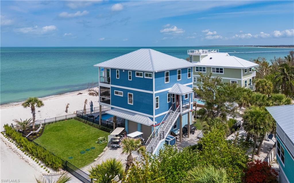 Gulf-front luxury living on the pristine beaches of North Captiva Island, offering a rare two-lot homesite with sweeping panoramic views of the Gulf of America, Captiva Pass, and Cayo Costa Island, where unforgettable sunsets unfold nightly. Thoughtfully designed for comfort, resilience, and effortless island living, this exceptional residence features a whole-house reverse osmosis system, private well and septic (not shared), a 1,000-gallon propane tank powering a full-house Kohler generator, propane gas range, and tankless water heater to ensure uninterrupted comfort. The gourmet kitchen is equipped with high-end appliances and expansive west-facing sliders that frame breathtaking water views and open seamlessly to indoor-outdoor entertaining. Outdoor living is elevated with expansive deck space, a shaded area beneath the home, outdoor refrigerator and icemaker, heated saltwater pool, six-person spa, full outdoor entertainment system, and outdoor shower—ideal for hosting or relaxing after a day on the water. The spacious climate-controlled garage includes air conditioning, room for golf carts, bicycles, beach gear, a workbench, and a convenient service elevator with a 300-lb capacity for groceries and luggage. The fully fenced yard offers manicured green grass and a sprinkler system, a rarity on the island. Zoned for weekly rentals, this property presents outstanding investment potential while remaining a serene private retreat. Ownership includes a one-year membership to the Island Club at North Captiva. Access is by private boat or ferry; overnight dockage is not included unless purchased separately, with two memberships available at Safety Harbor offering dockage and amenities—contact Safety Harbor for details. The private airstrip is available to members only through the Salty Approach association. A truly rare opportunity to own a Gulf-front estate with scale, privacy, and flexibility—this two-lot offering delivers endless possibilities and will not last. Schedule your private showing today!