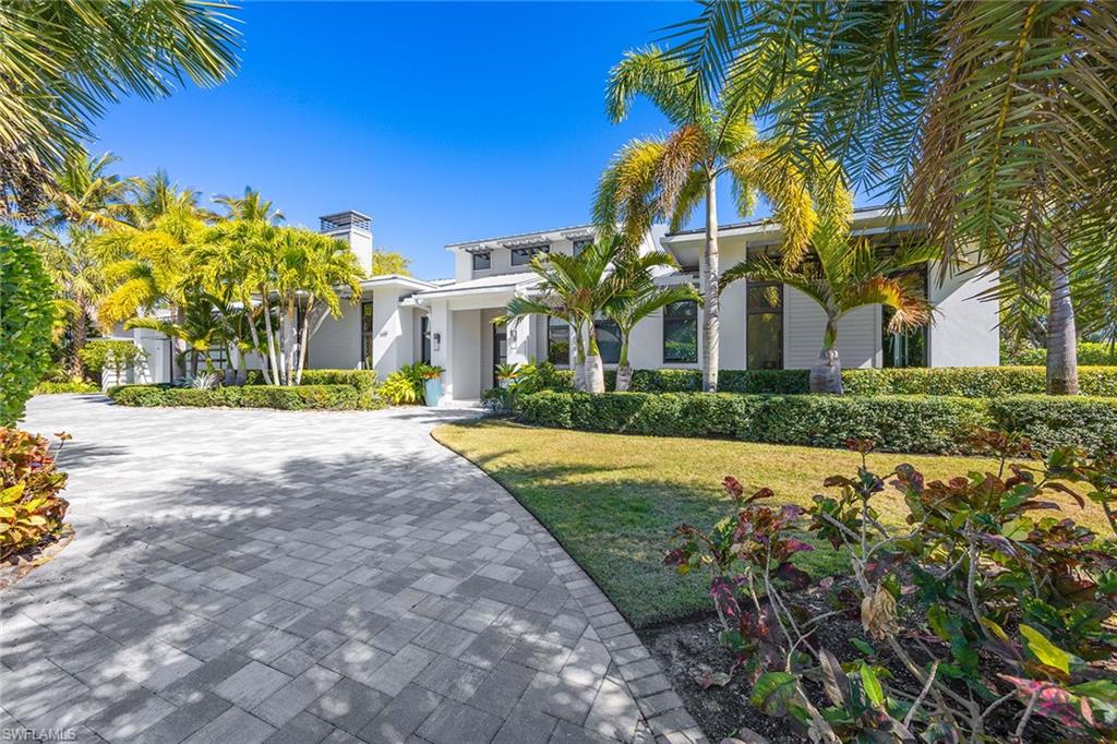 On an exceptionally large and private corner lot in one of Naples exclusive neighborhoods, this custom residence, designed by acclaimed architect Jonathan Kukk, is just a short visit to white sand beaches and the new Four Seasons Resort. Spanning more than 6,500 total square feet, the home includes five spacious bedrooms and six baths. Interiors by Design West, complemented by a curated furnishings package, reflect a warm, modern coastal aesthetic. Soaring 21-foot ceilings and stained wood accents lend architectural presence, while expansive impact-resistant doors and windows fill the home with natural light. Luxury finishes, including Ruffino custom cabinetry and Legno Bastone white oak flooring, are carried throughout. Pocketing sliders open to a lush outdoor retreat with a large covered lanai, roll-down screens, shell stone decking, a resort-style pool and spa, an outdoor kitchen and fire pit. The home is equipped with a whole-house generator and is positioned in an X flood zone, offering peace of mind. Just minutes from downtown Naples, this residence presents a rare combination of scale, privacy and design in one of Naples premier beachside locations.