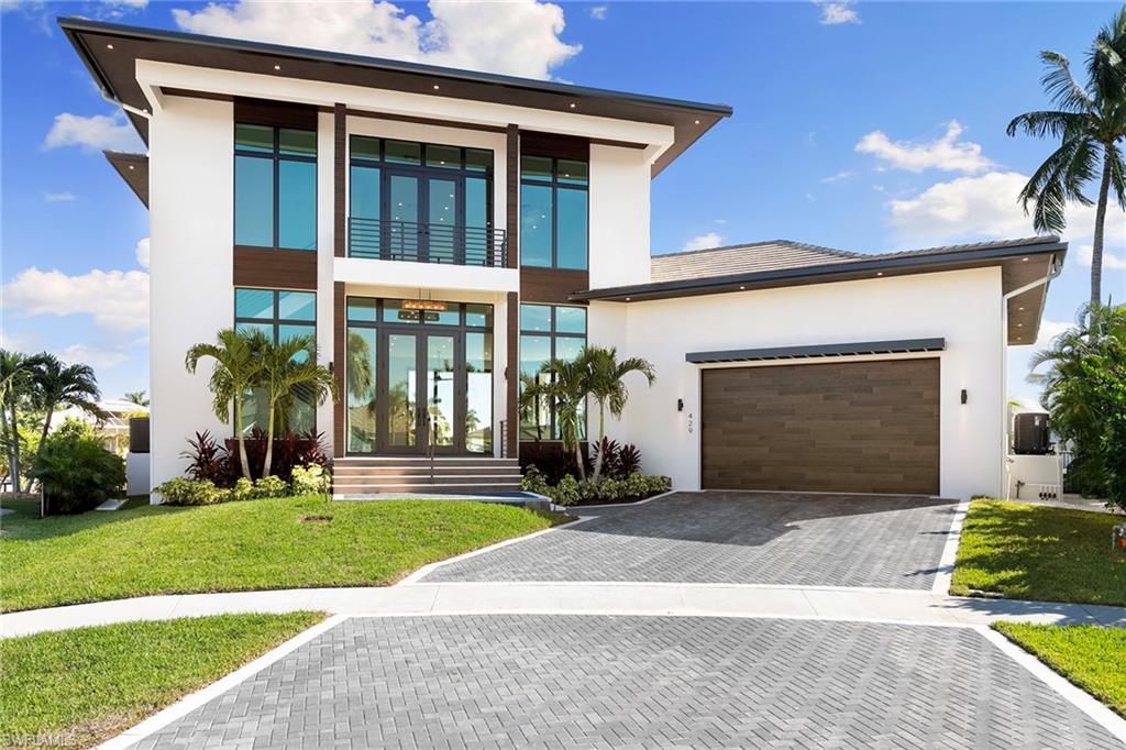 This new, magnificent custom-built home offers luxurious waterfront living with four bedrooms and four and a half baths. On an exceptional oversized tip lot with 163 feet of waterfront, the property boasts breathtaking intersecting wide-water canal views. It is conveniently just a short boat ride from Roberts Bay and the Gulf. Modern Contemporary Design, this spectacular two-story residence encompasses over 4,400 square feet of air-conditioned living space. Upon entry, you are welcomed by a spacious open-concept great room featuring beautiful custom built-in cabinetry. This area seamlessly connects to a chef’s dream kitchen, equipped with a large island and breakfast bar, a gas cooktop, stunning custom cabinets and a wine cooler. The first floor includes a ½ pool bath, and luxurious primary suite retreat, providing comfort and privacy. In addition, a guest en suite is conveniently on this level for visiting friends or family. Upstairs, you will find two additional en-suite bedrooms, each offering privacy and comfort. A wet bar with a wine cooler enhances the entertainment options, while the private covered open lanai, sun deck, and comfortable family room provide ample space for relaxation and gathering with loved ones. The expansive open outdoor living area features a sparkling pool, spa and built-in gas grill, making it ideal for entertaining or unwinding in the beautiful surroundings. This home is equipped with impact-glass windows and doors throughout, ensuring safety and energy efficiency. Additional amenities include engineered wood and tile floors throughout, two air-conditioning units, two tankless hot water tanks, a 500-gallon propane gas tank and a transfer switch installed for a generator. Newer seawall, installed in 2009. Do not miss this opportunity to own this stunning waterfront custom home, where luxury and comfort meet exceptional design and location.
