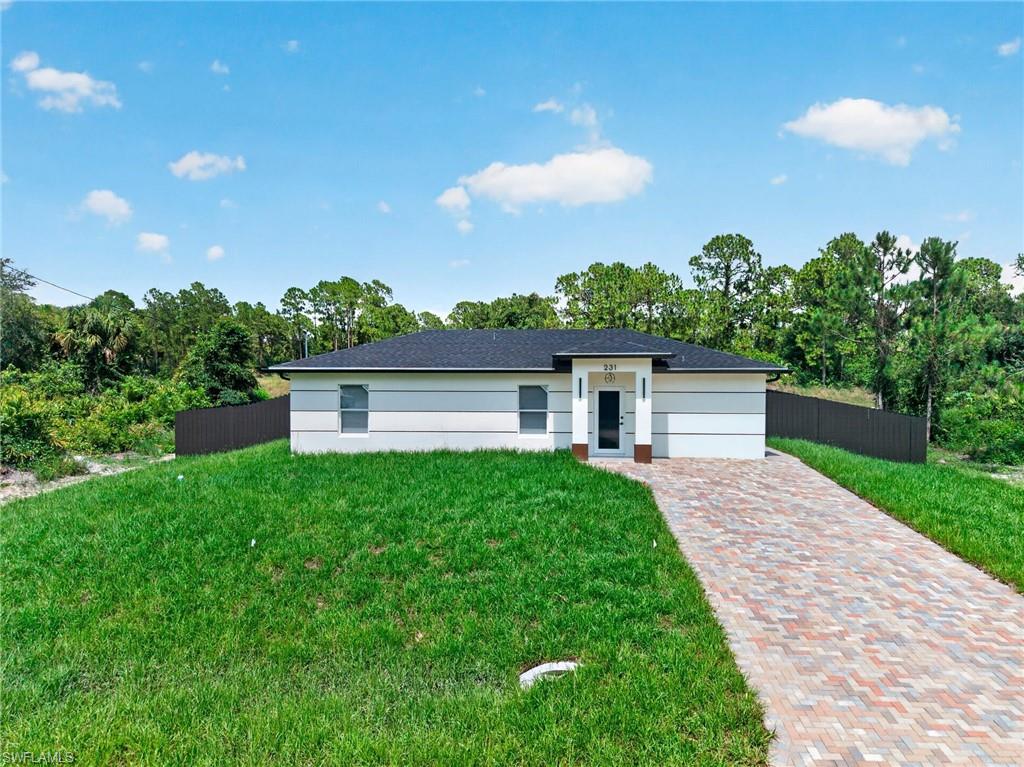 Thoughtfully designed with modern style and functionality in mind, beautifully crafted 3 bedroom, 2 bath home offers an open concept layout enhanced by porcelain tile flooring, quartz countertops, contemporary cabinetry, and a striking wood-accent island.  Step outside to a covered paver lanai overlooking a fully fenced backyard, creating the perfect space for relaxing or entertaining year-round. Extended paver walkways provide convenient access around the home, while a tankless water heater and LED exterior lighting add efficiency, space and curb appeal. The spacious primary suite features a walk-in closet and a beautifully finished bathroom with a frameless glass shower and floor-to-ceiling tile. Ideally located near schools, shopping, and everyday conveniences, this move-in-ready home blends modern design, comfort, and value in one.