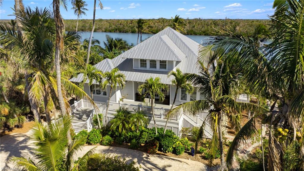 MAIN HOME IS 3 BEDROOM 2 1/2 BATHS AND ELEVATED. GUEST HOUSE IS 2 BEDROOMS 1 BATH AND THE COTTAGE IS 1BEDROOM 1 BATH. This secluded Captiva Island estate unfolds like a secret whispered along the shores of Roosevelt Channel, where privacy and natural beauty blend into an atmosphere of pure coastal enchantment. Approached by a modest shell drive softened by lush vegetation, the entrance is marked only by a discreet sign: Le Jardin: The Garden. It is an invitation into another world, where tropical abundance greets you in every direction. Swaying palms, fragrant citrus groves, and vivid blooms guide your journey through nearly two acres of waterfront paradise. As the winding drive gently curves beneath the canopy of greenery, the estate slowly reveals itself. At its heart stands an exquisite Old Florida inspired residence, perfectly poised along the serene waters of the channel. With three bedrooms and two and a half baths, the main home evokes the timeless romance of Florida’s classic coastal architecture, offering stunning water views from almost every room. Inside, the expansive kitchen becomes a natural gathering place, centered around a gas range ideal for culinary celebrations. Here, lingering conversations unfold beside the warmth of the fireplace, while large porches just beyond invite you to breathe in the salt-kissed breeze and watch as dolphins play and boats drift by in the afternoon sun. Steps from the water, your private dock extends into the channel, complete with two boat lifts ready to host your adventures. The days here are effortlessly filled with the best of island living: setting out on the boat to fish or explore nearby islands, cruising to waterfront restaurants, or slipping a kayak into the calm blue water to paddle toward the untouched sanctuary of Buck Key just across the channel. For quieter moments, a thatched tiki hut offers peaceful shade along the shoreline where you can savor the stillness of the island. Meandering deeper into the property, you arrive at the charming two bedroom pool house. Beamed ceilings soar above a warm, inviting space anchored by a stone fireplace. A kitchenette, relaxed seating areas, and game spaces encircle the screened swimming pool, creating a private oasis for effortless entertaining and unforgettable gatherings. Further along the shell path, a generous garage and storage building awaits, designed to shelter everything from bicycles and beach gear to kayaks and boating essentials. At the very end of the lane, tucked elegantly within the gardens, sits a picturesque guest cottage complete with a full kitchen, living room, bedroom, and bath. It is an intimate hideaway perfect for visiting friends or attentive caretakers, enveloped in the tranquility of nature. Le Jardin is more than an estate; it is an experience.