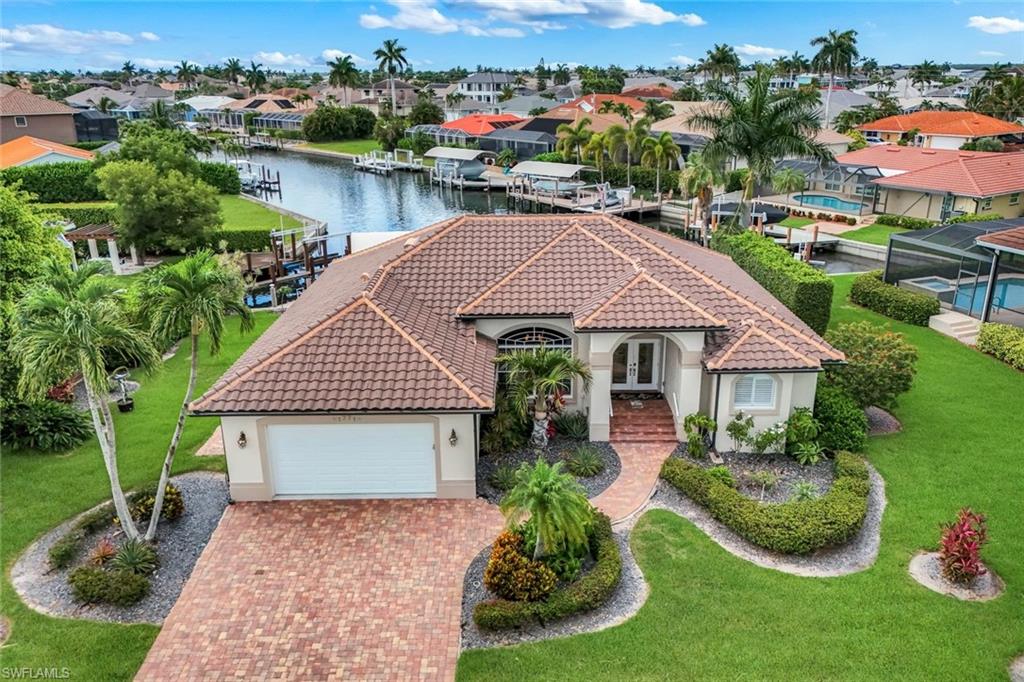 Waterfront living takes center stage at this beautifully maintained Marco Island residence offering 102 feet of waterfrontage, a wide and long water view, and an oversized 0.26-acre homesite with extra side-yard space rarely found. Designed to embrace the setting, the pool lanai features picture-window screening to maximize the view, travertine marble decking, multiple lounging and dining areas, recessed ceilings with rope lighting, and a covered outdoor living space ideal for entertaining or relaxing poolside. The resurfaced and re-tiled pool is enhanced by four laminar water features and a new 150,000 BTU heat pump. Boaters will appreciate the composite dock with stainless steel hardware, a new removable boat lift canopy installed in 2025, and convenient Gulf access on the Marco River. Inside, vaulted ceilings and an open living and dining area create a bright, welcoming atmosphere. Porcelain tile flooring, crown molding, plantation shutters, and expansive water views complement the living spaces, while the kitchen offers granite countertops, stainless appliances, a breakfast bar, and a bay-window dining area overlooking the water. The primary suite features engineered hardwood flooring, a California king adjustable bed, walk-in closet, dual vanities, soaking tub, rain shower, and linen tower. A guest bedroom opens directly to the lanai, while a bunk room accommodates three. Smart home technology provides remote control of the irrigation, pool, thermostat, water heater, lighting, fans, and water systems, simplifying seasonal ownership and property management. Future rental reservations may provide added income potential. Additional features include automatic and manual hurricane shutters on most openings and on the lanai, a 2017 roof, insulated impact-rated garage door, mature tropical landscaping, attached two-car garage, and turnkey furnished interiors. Conveniently located near North Barfield Drive for easy access on and off the island, this property combines boating, outdoor living, and modern convenience in one exceptional Marco Island offering.