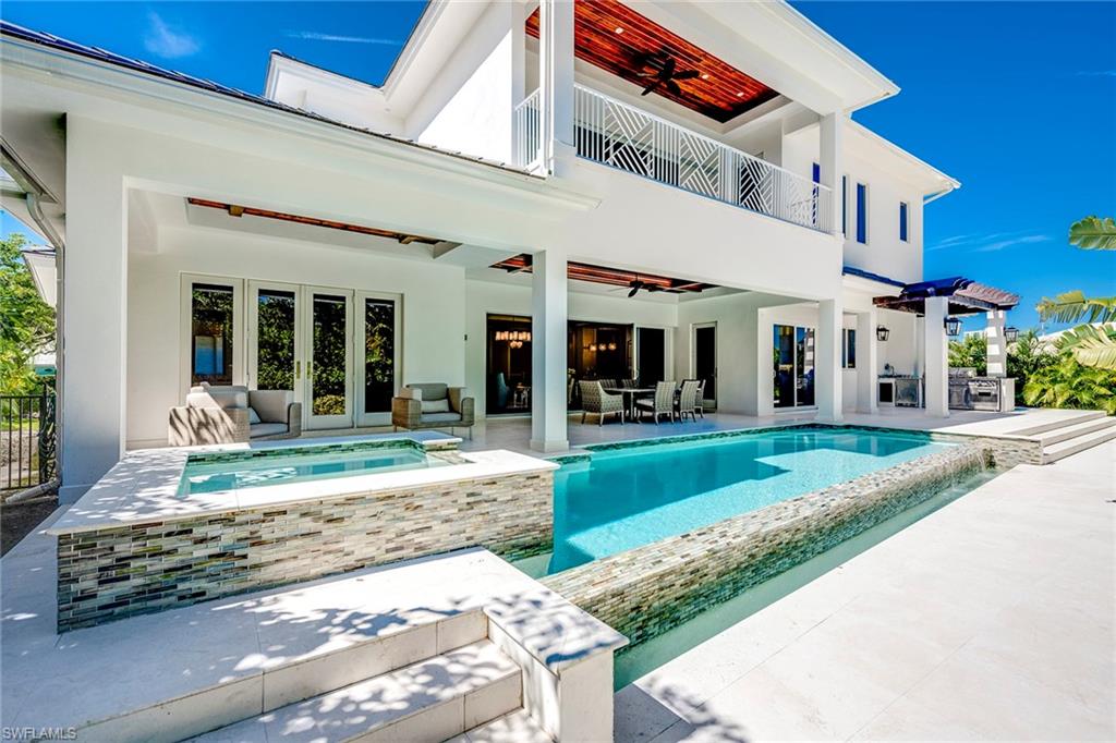This Park Shore designer home will raise your standards of luxury living. Timeless and elegant but built like a fortress with solid concrete walls and impact glass throughout making this coastal contemporary home virtually indestructible. Over 5,000 square feet encompasses two stories of living area perfectly designed for today’s modern family - an expansive great room with endless views of the large and lushly landscaped outdoors, gourmet kitchen, walk-in wine cellar and bar, dining room, den and retreat-like master en-suite bedroom. Designed by award-winning architect Don Stevenson and furnished by Robb & Stucky, the uniqueness of this property is highlighted by timeless natural materials including Legno hardwood flooring and classically detailed millwork with custom cabinetry, elaborate moldings and ceiling detail. A second floor considers all your guests' needs with a second master bedroom, spacious entertainment loft, separate laundry room, three balconies - two for western sunsets and the other overviewing the first-floor infinity edge pool and spa - and two more en-suite guest rooms. Offering enduring excellence, this luxe home is a cut above the rest.