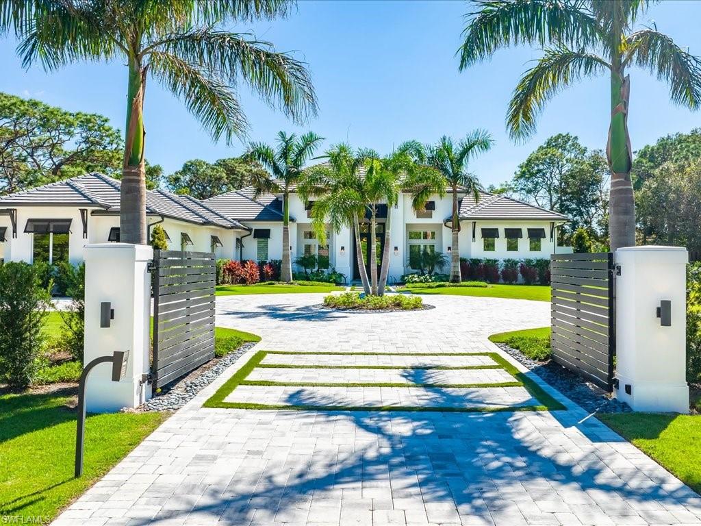 Captivating and stylish, this single-story Naples home set on 1.37 acres in the sought-after Pine Ridge Estates is one you're sure to admire. Manicured gardens and a gated circular driveway welcome you inside this 1-year-old residence where you'll discover high-end finishes and innovative design details throughout. French doors usher you into the expansive living room where vaulted ceilings are enhanced by exposed beams, large glass sliders frame your outdoor oasis, and a linear fireplace is flanked by sleek built-in shelving. Your seamlessly connected kitchen has an oversized multi-seater island, stainless steel appliances, gorgeous white cabinetry, and a pantry with a wine chiller. The luxurious proportions of the primary suite treat you to direct outside access, a walk-in closet with built-in organizers, and an opulent ensuite with a freestanding soaking tub and a two-person, multi-head shower. Enjoy ultimate outdoor entertaining on the covered south-facing patio with multiple sitting spaces, a built-in kitchen, a pristine pool with a spa, and a fireplace. As a bonus, you'll have a family room, an office, a laundry room, and an attached 3-car garage. Come for a tour today!